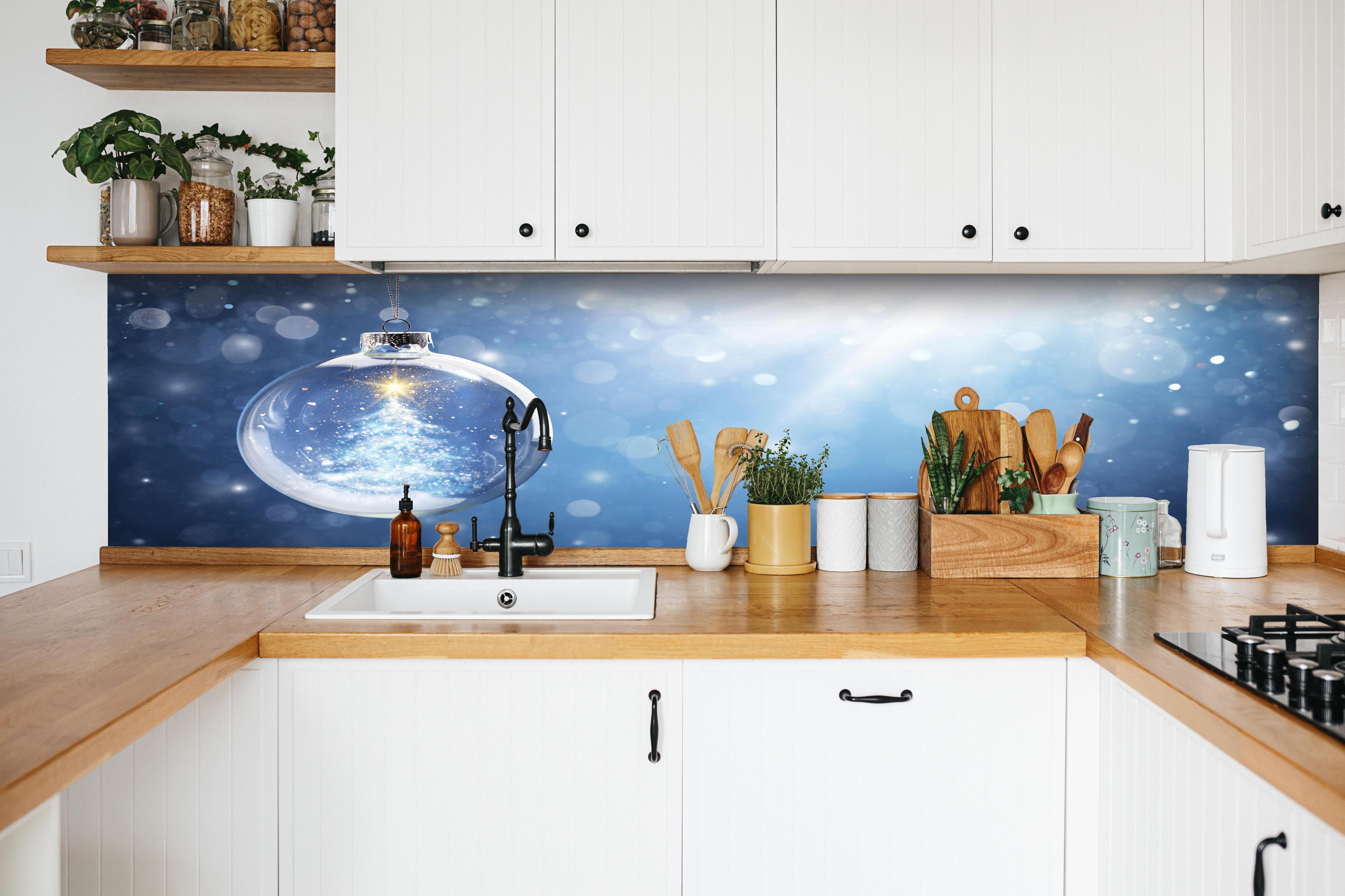 Küche - Glänzender Weihnachtsbaum in Schneekugel hinter weißen Hochglanz-Küchenregalen und schwarzem Wasserhahn