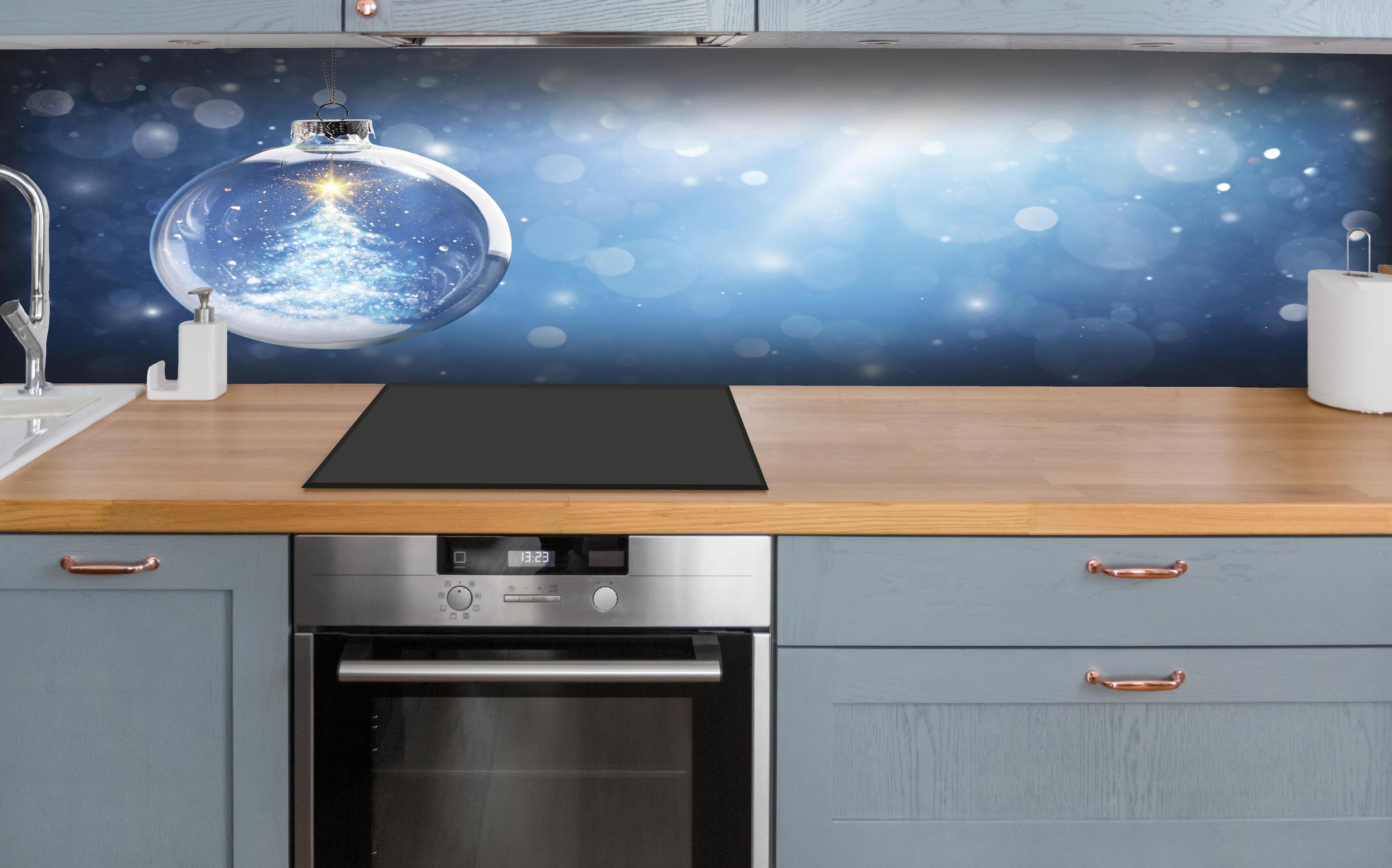 Küche - Glänzender Weihnachtsbaum in Schneekugel hinter weißen Hochglanz-Küchenregalen und schwarzem Wasserhahn