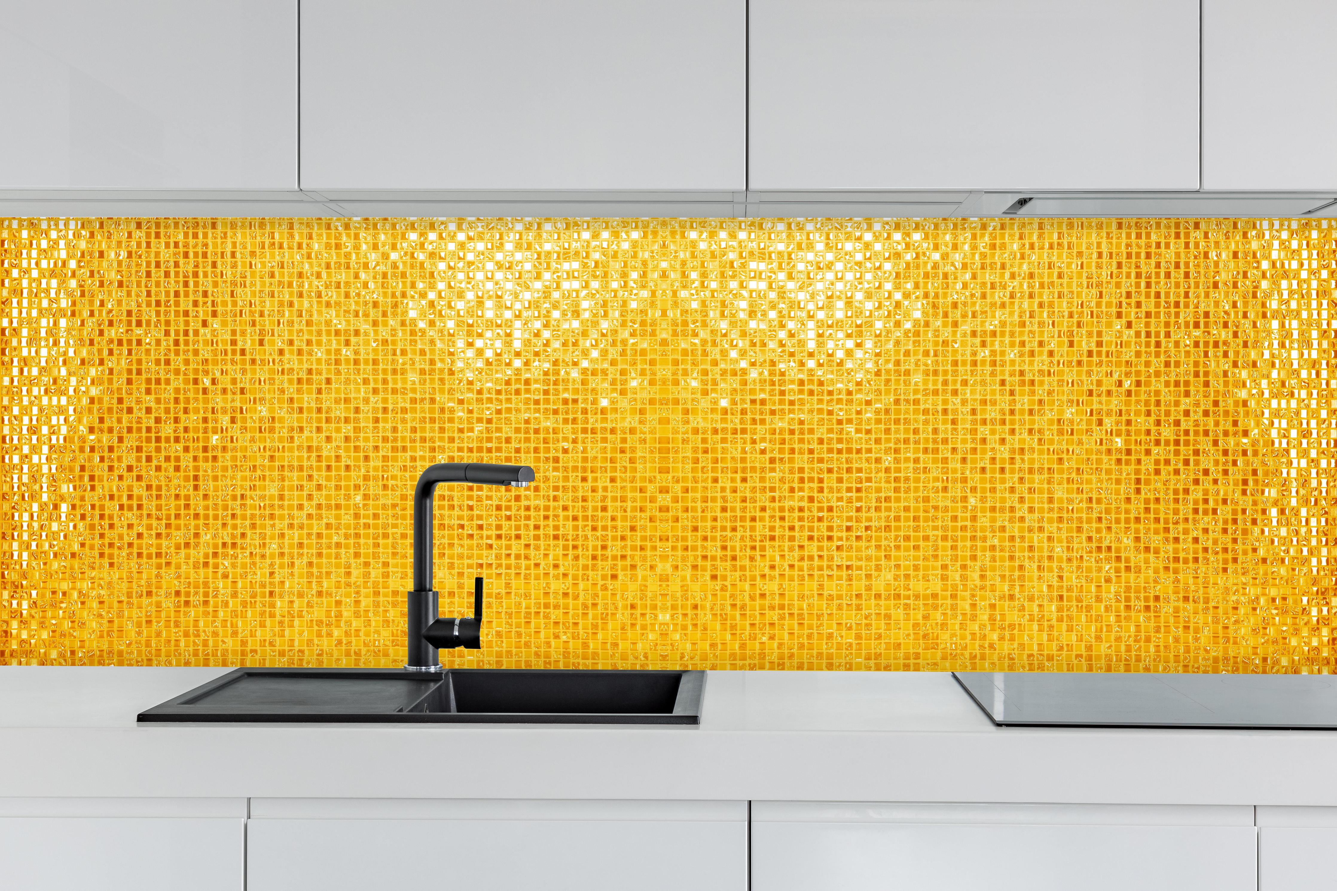 Küche - Goldgelbe Mosaikfliesen hinter weißen Hochglanz-Küchenregalen und schwarzem Wasserhahn