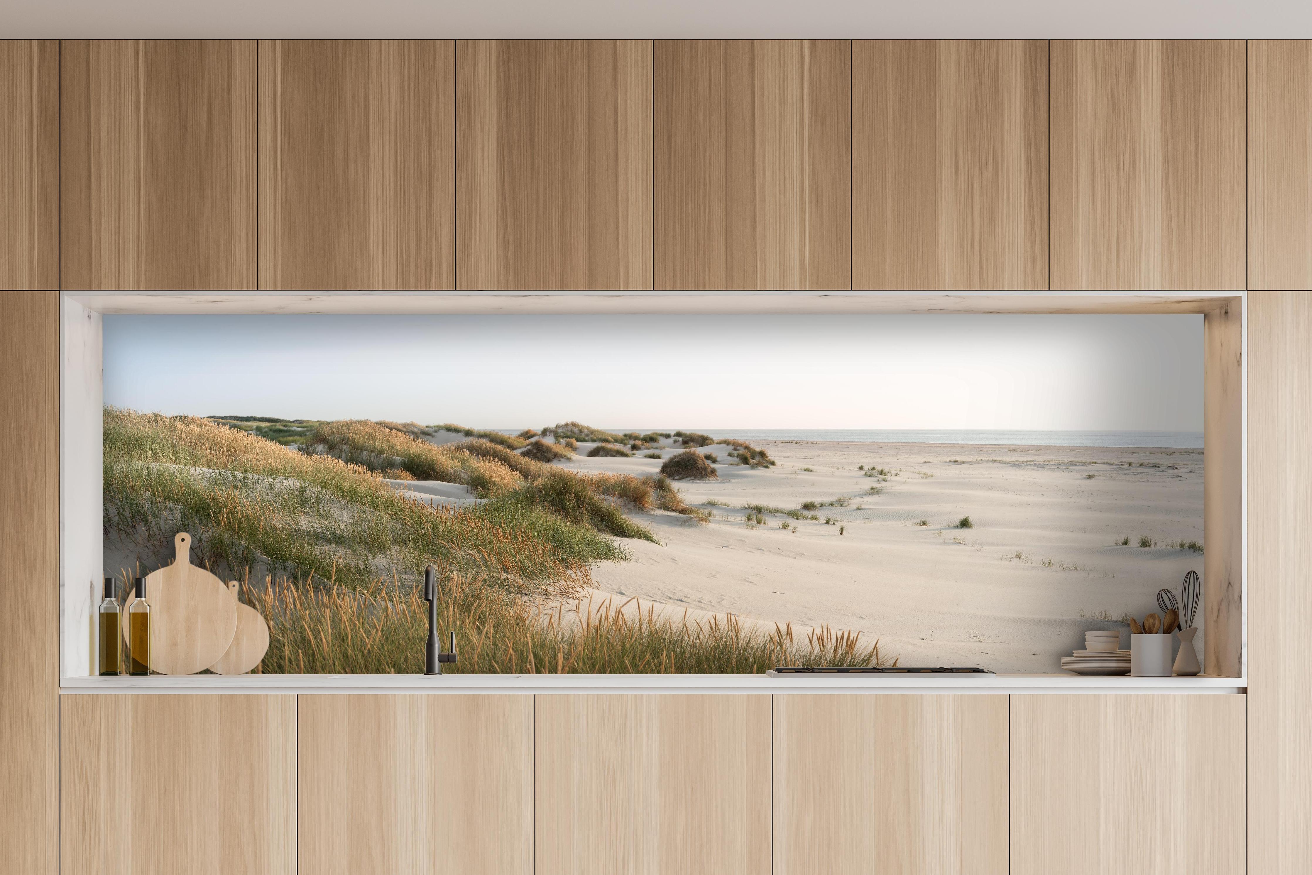 Küche - Harmonische Strandlandschaft mit sanften Sanddünen und Strandgräsern hinter weißen Hochglanz-Küchenregalen und schwarzem Wasserhahn