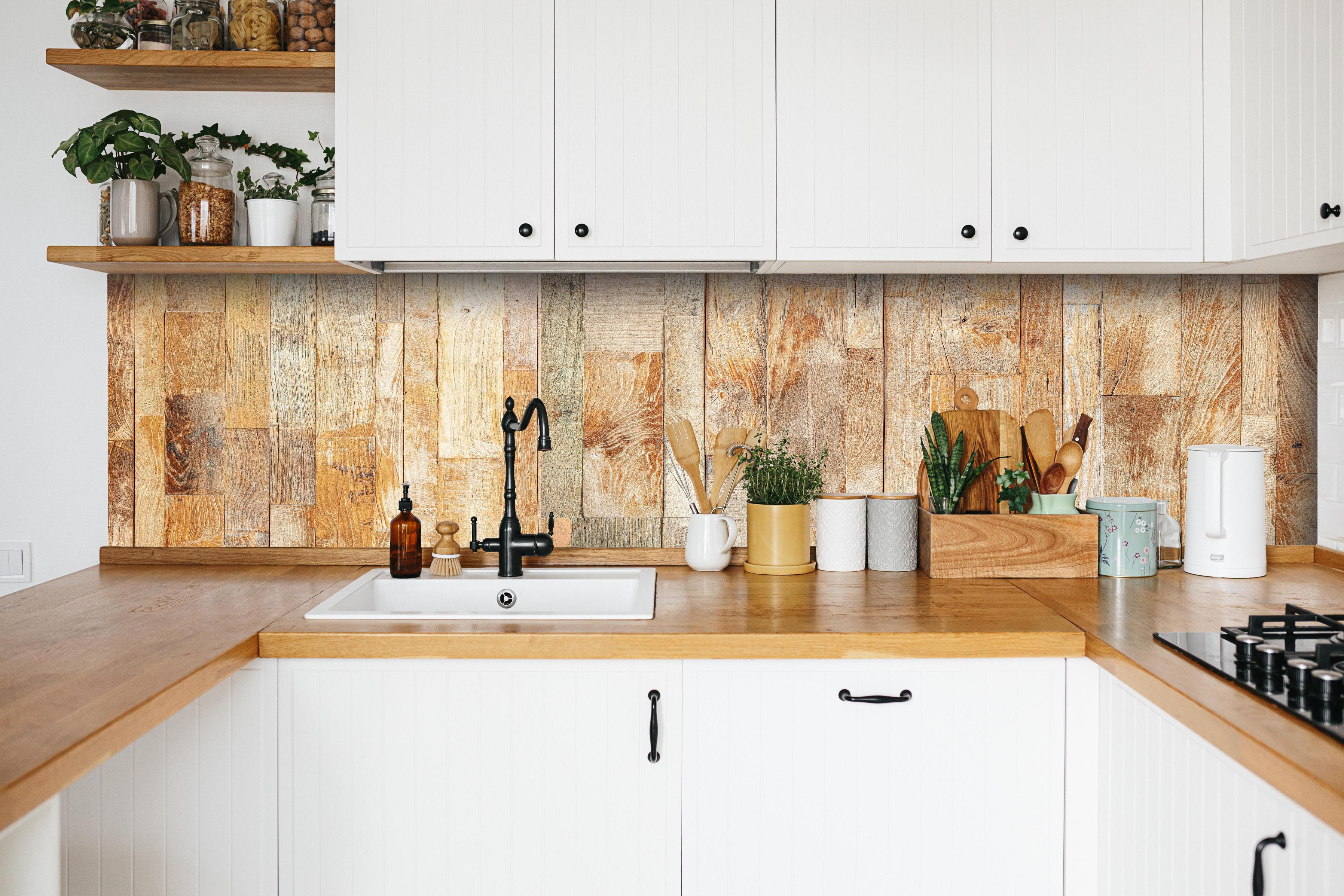 Küche - Heller Holzhintergrund hinter weißen Hochglanz-Küchenregalen und schwarzem Wasserhahn