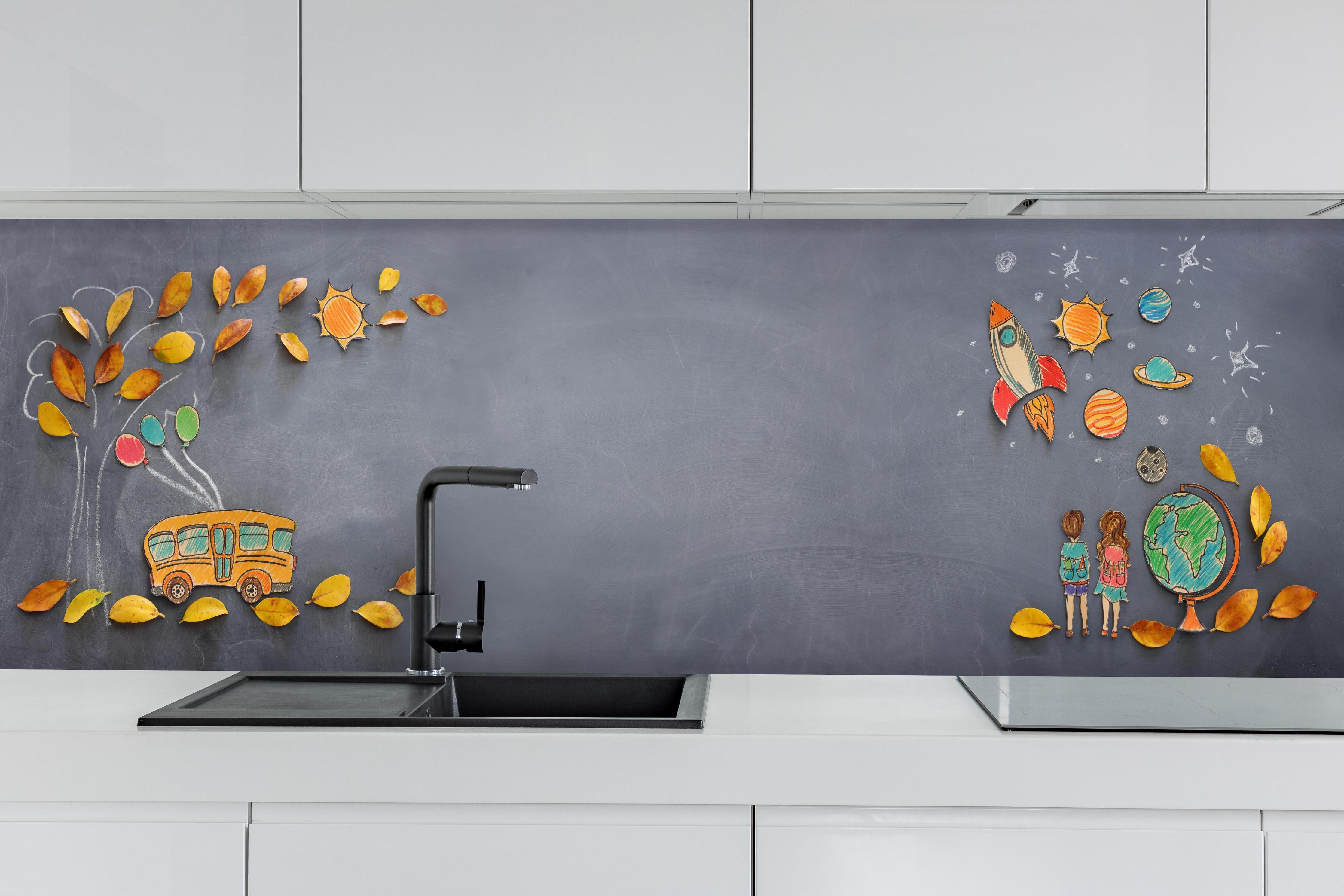 Küche - Herbstleaves und Schulbus auf Tafel hinter weißen Hochglanz-Küchenregalen und schwarzem Wasserhahn