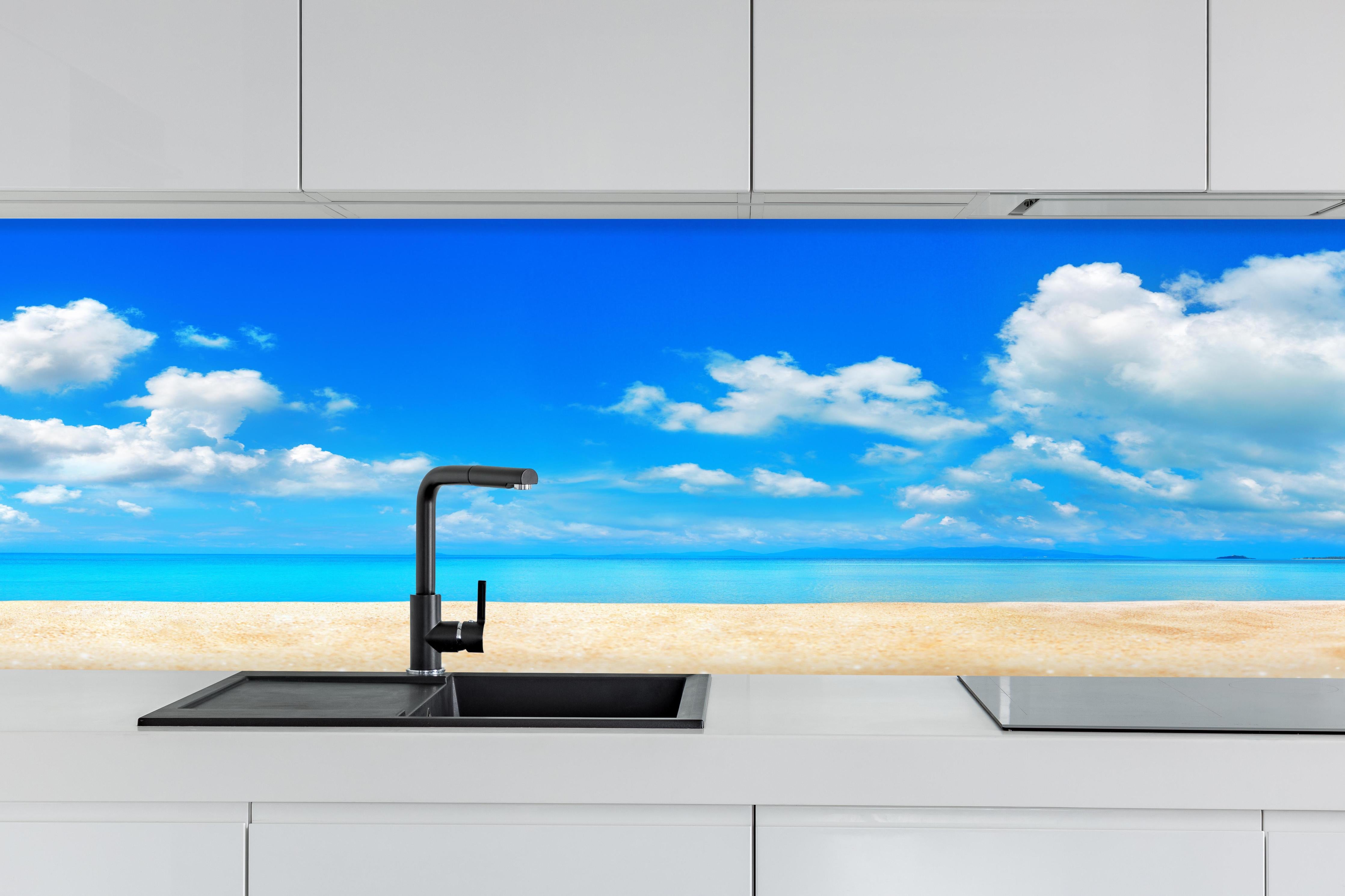 Küche - Idyllische Strandlandschaft mit klarem Wasser und blauem Himmel hinter weißen Hochglanz-Küchenregalen und schwarzem Wasserhahn
