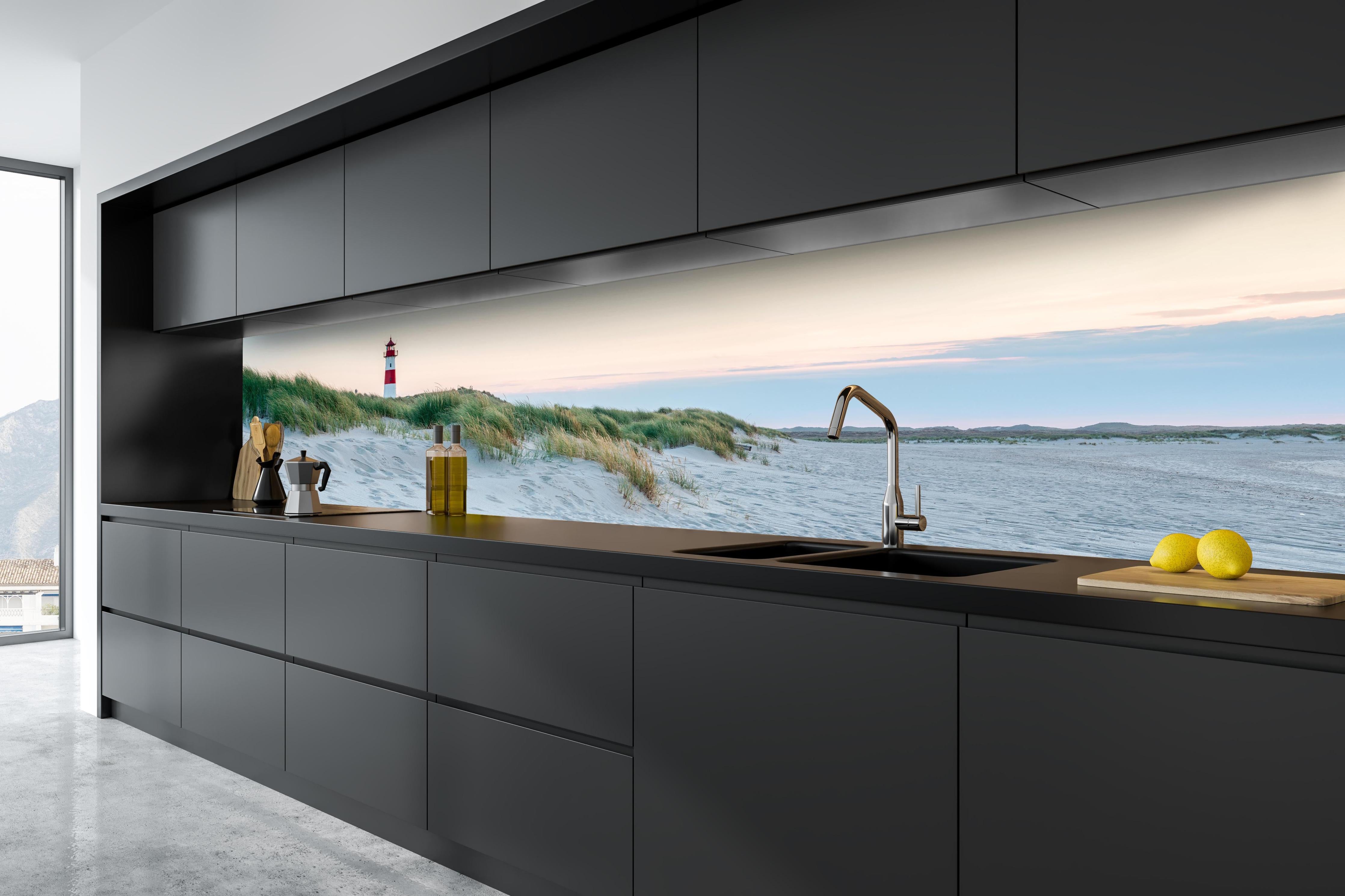 Küche - Idyllischer Leuchtturm zwischen Sanddünen und sanften Wellen hinter weißen Hochglanz-Küchenregalen und schwarzem Wasserhahn