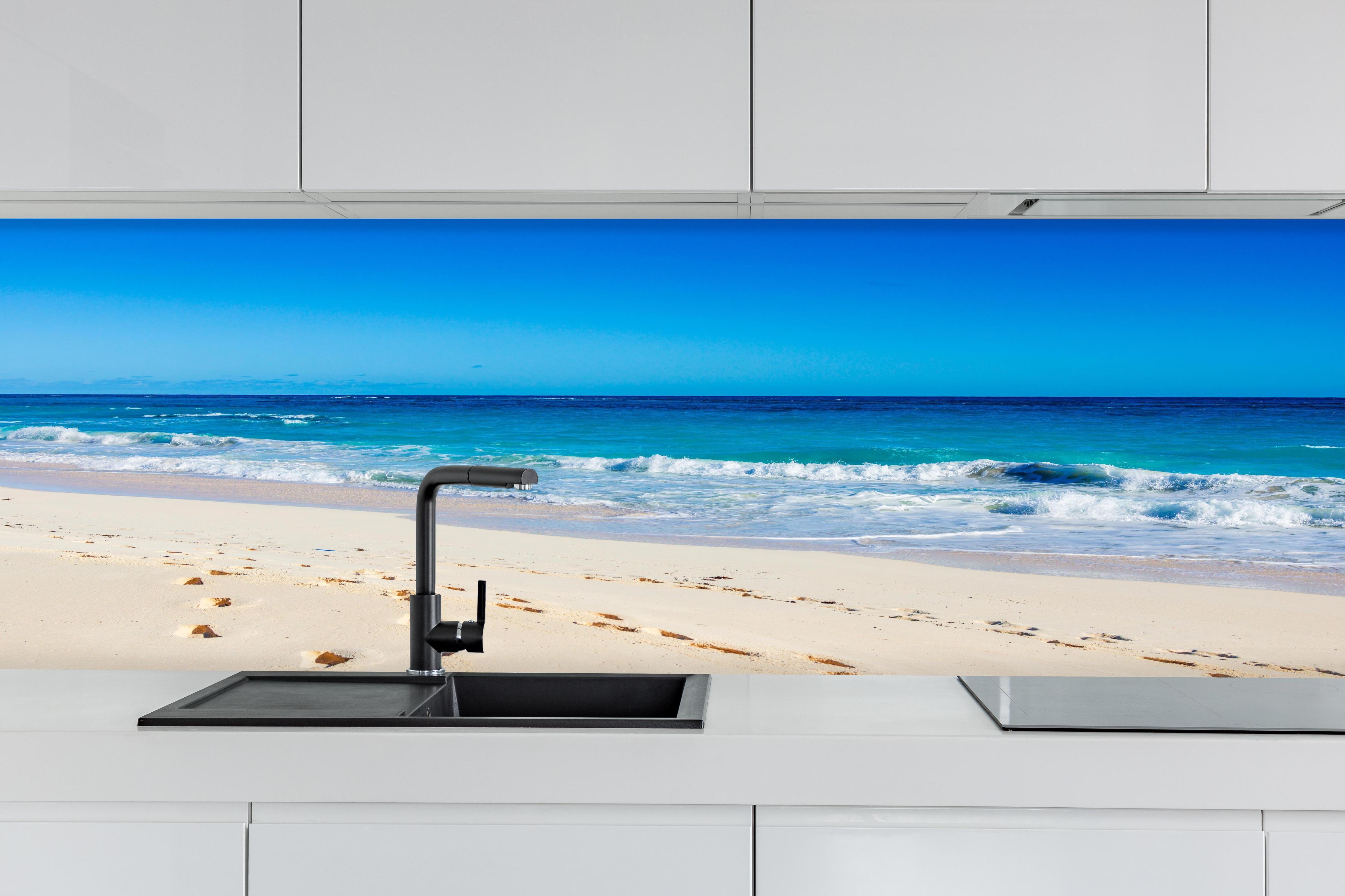 Küche - Idyllischer Strand mit feinem Sand und türkisfarbenem Wasser hinter weißen Hochglanz-Küchenregalen und schwarzem Wasserhahn