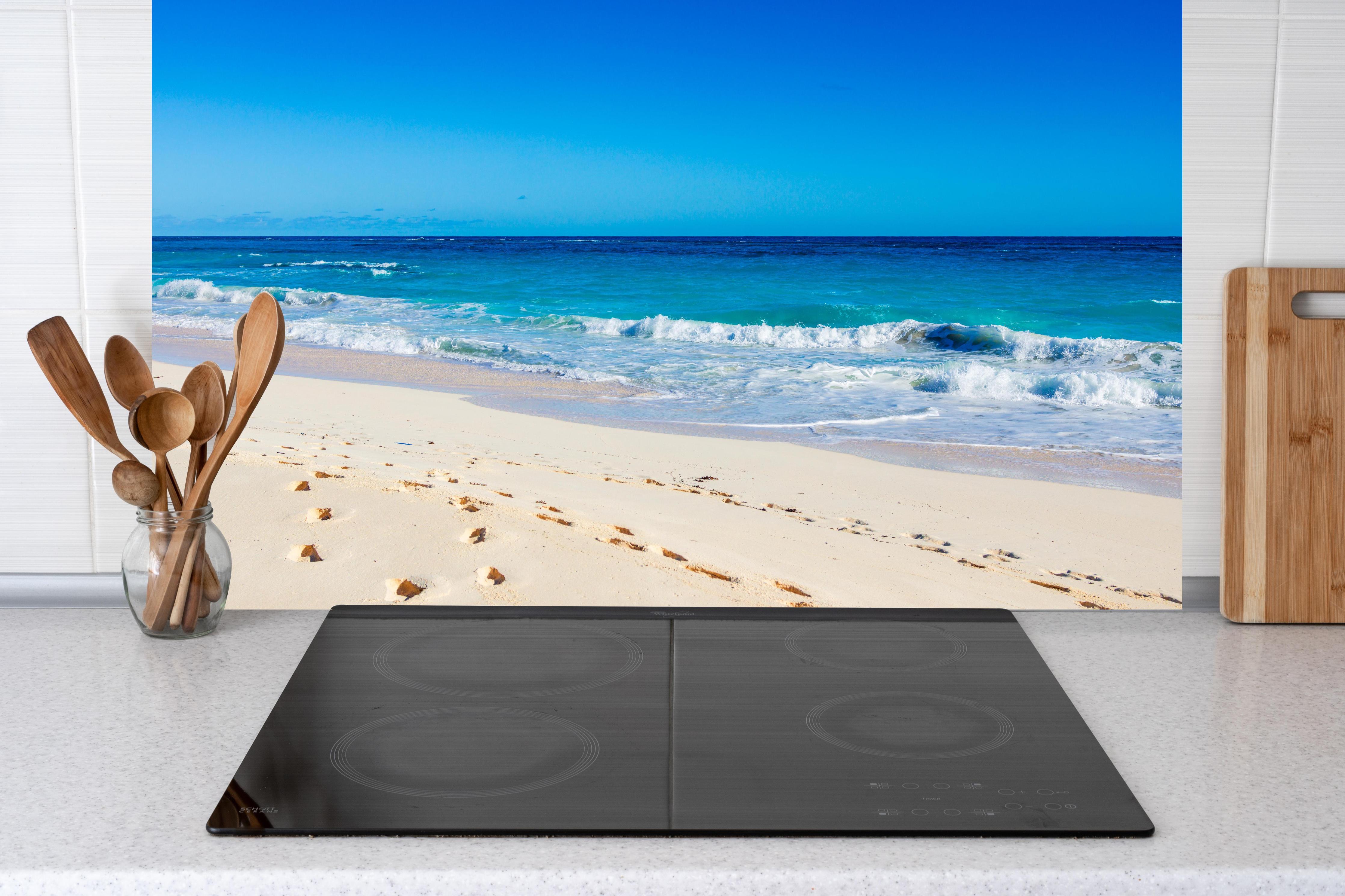 Küche - Idyllischer Strand mit feinem Sand und türkisfarbenem Wasser hinter weißen Hochglanz-Küchenregalen und schwarzem Wasserhahn