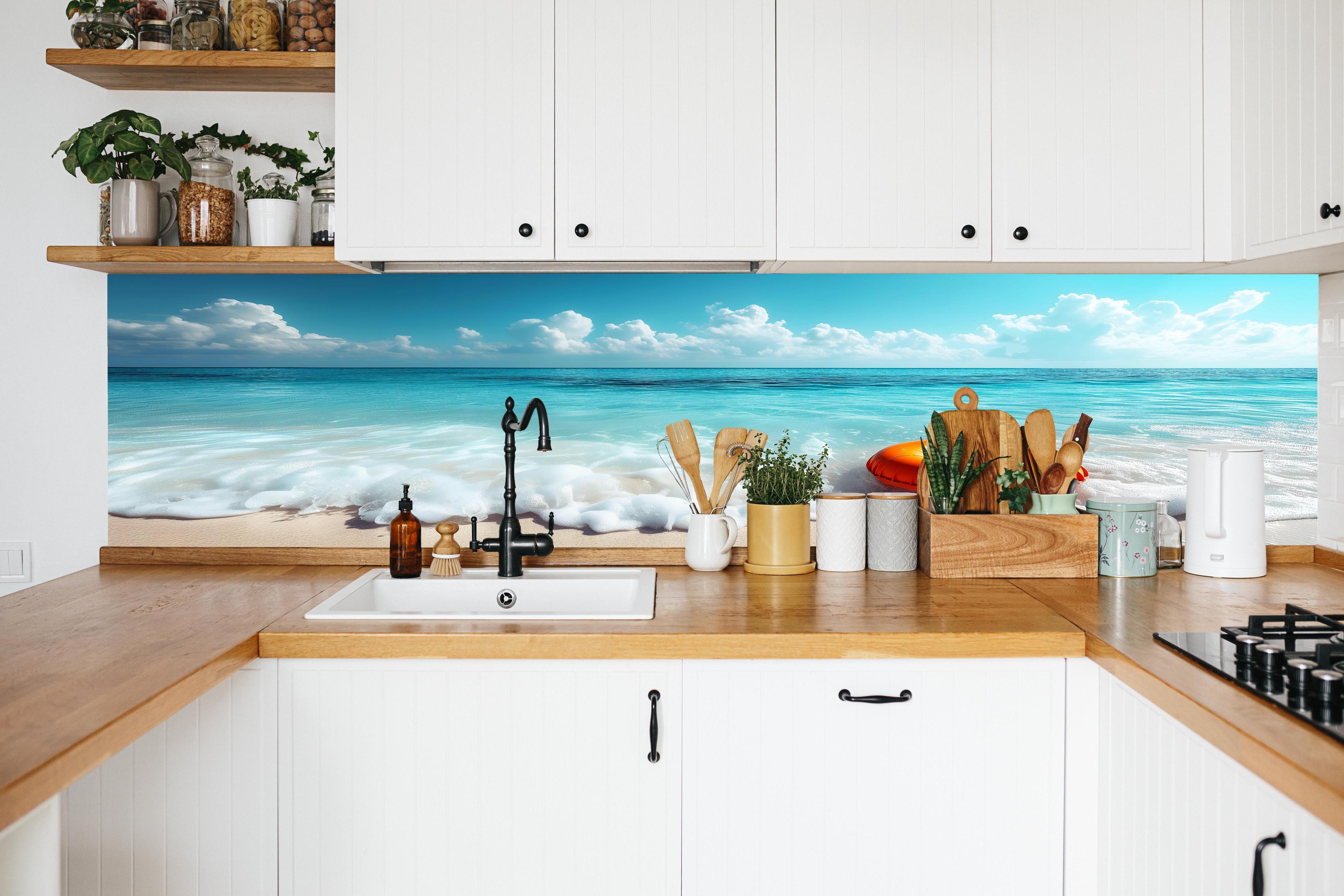 Küche - Idyllischer Strand mit orangefarbener Schwimmringen und klarblauem Wasser hinter weißen Hochglanz-Küchenregalen und schwarzem Wasserhahn