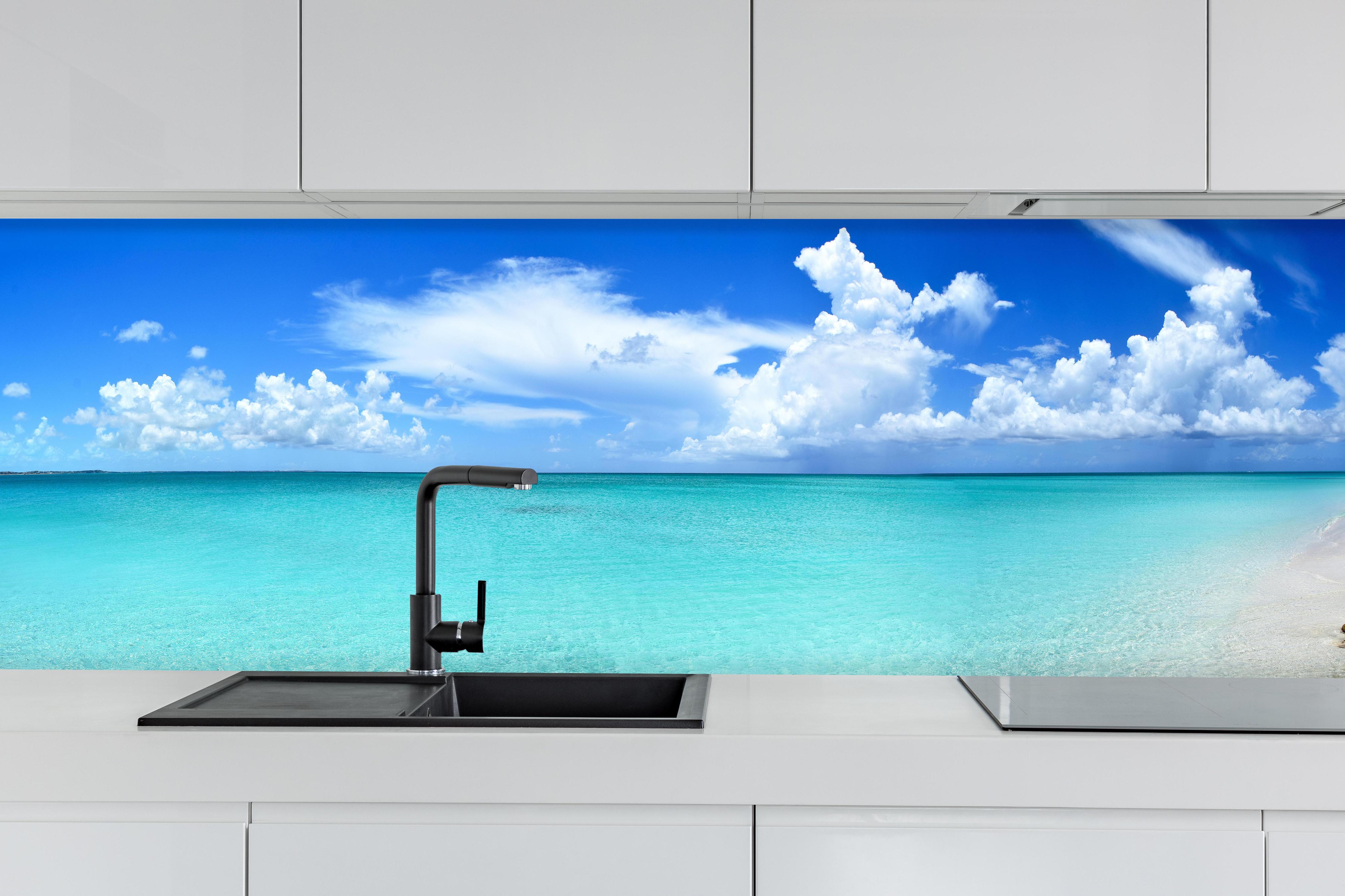 Küche - Idyllischer Strand unter einem strahlend blauen Himmel hinter weißen Hochglanz-Küchenregalen und schwarzem Wasserhahn