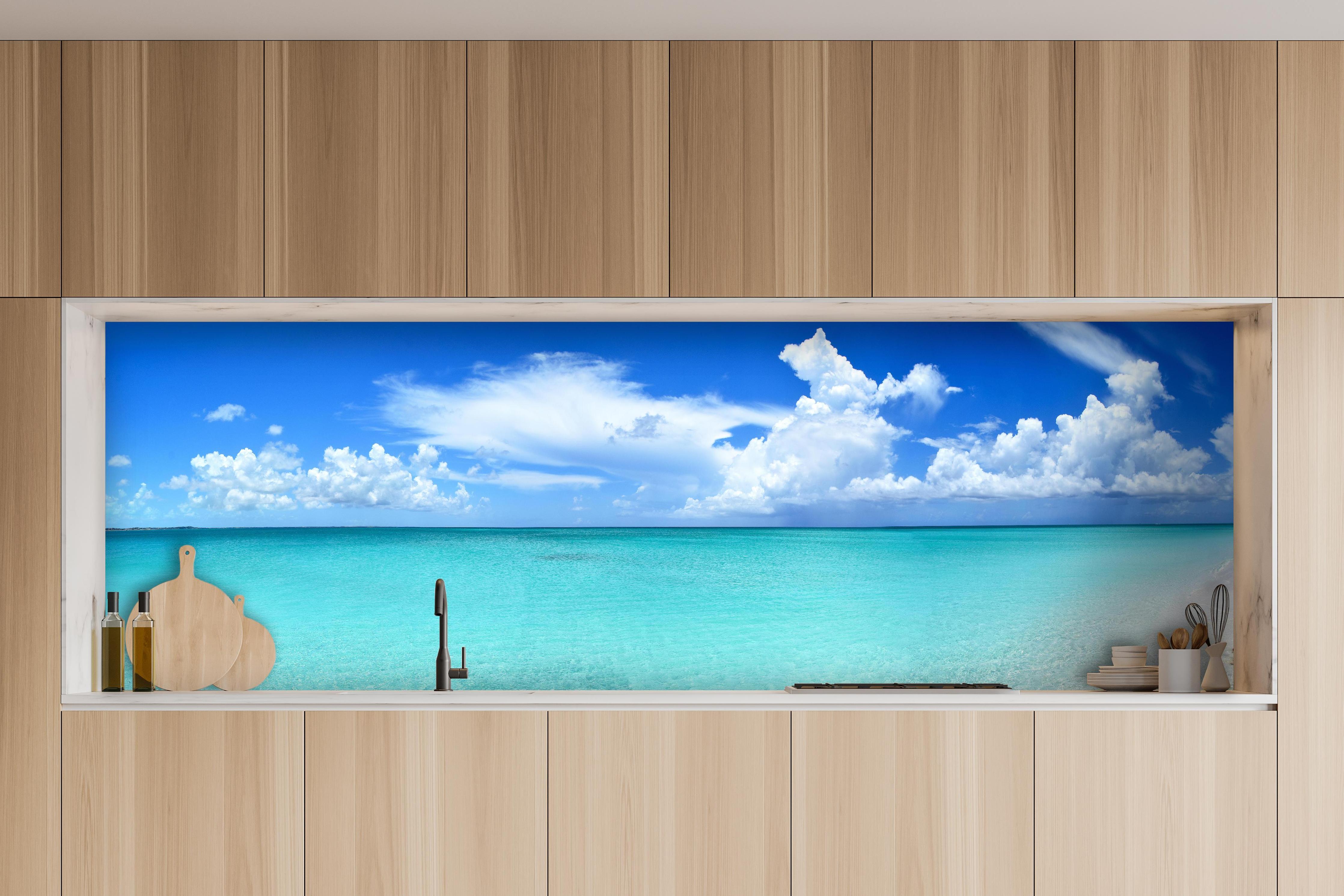 Küche - Idyllischer Strand unter einem strahlend blauen Himmel hinter weißen Hochglanz-Küchenregalen und schwarzem Wasserhahn