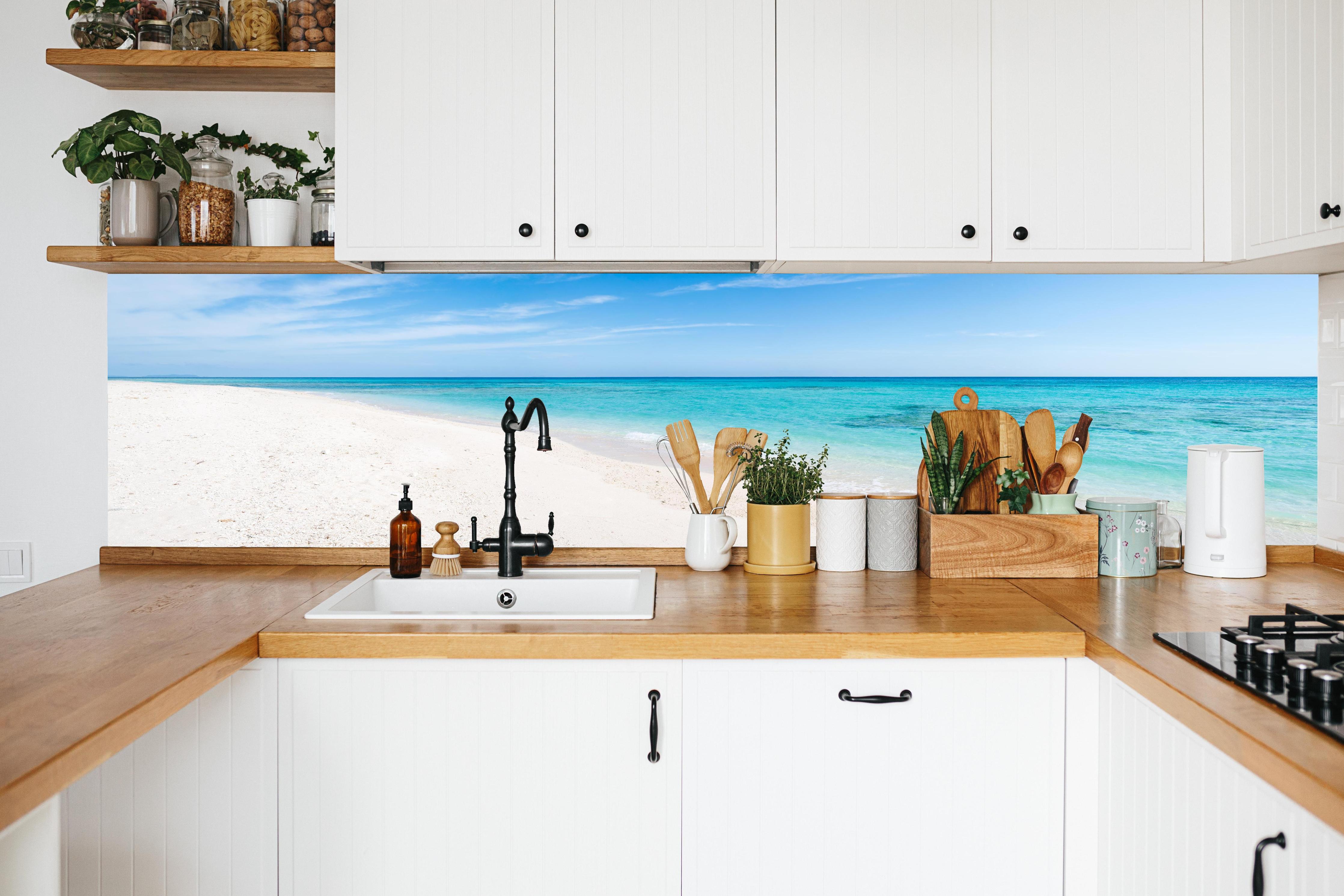 Küche - Idyllischer karibischer Strand mit strahlend blauem Wasser und feinem Sand hinter weißen Hochglanz-Küchenregalen und schwarzem Wasserhahn