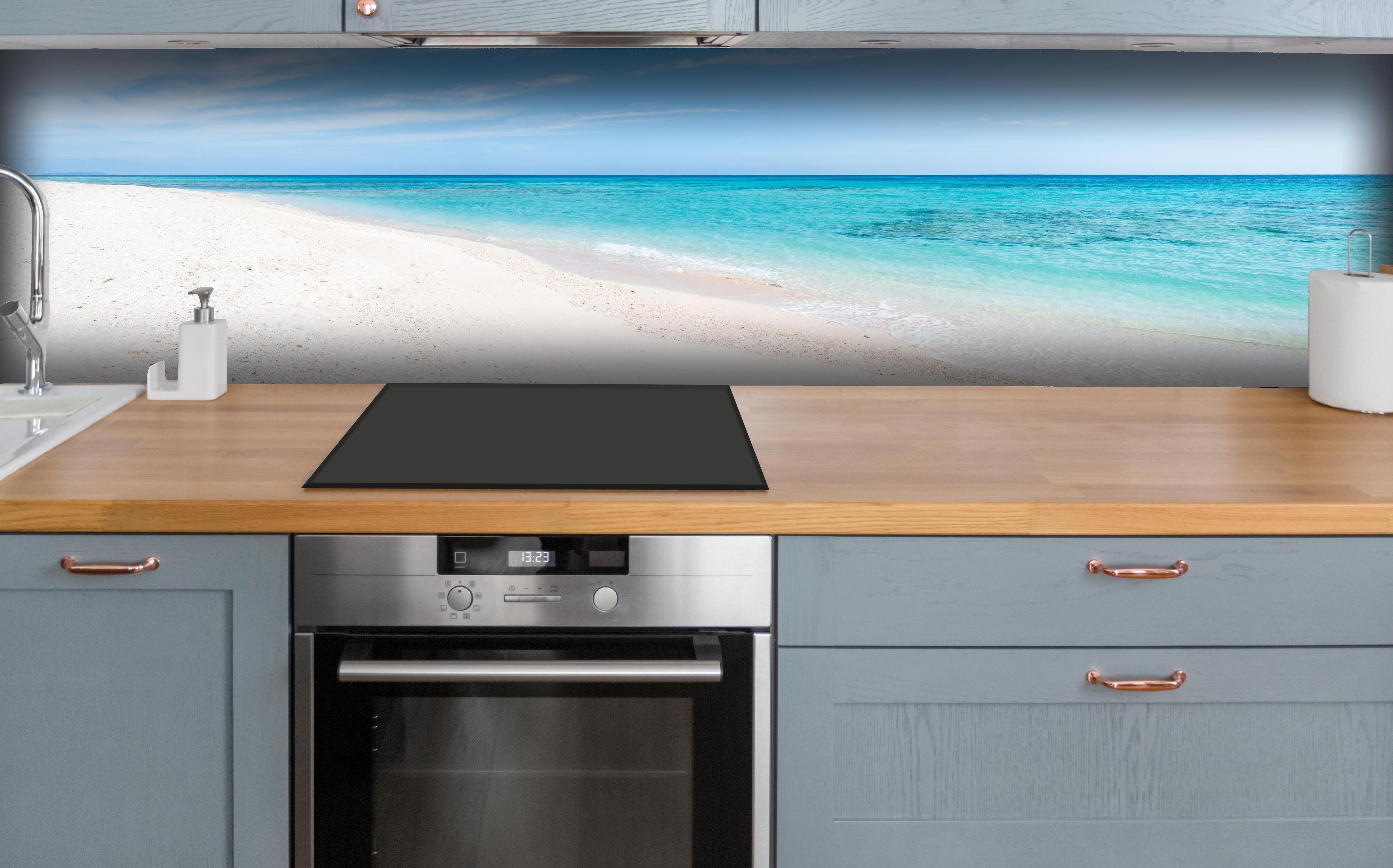 Küche - Idyllischer karibischer Strand mit strahlend blauem Wasser und feinem Sand hinter weißen Hochglanz-Küchenregalen und schwarzem Wasserhahn