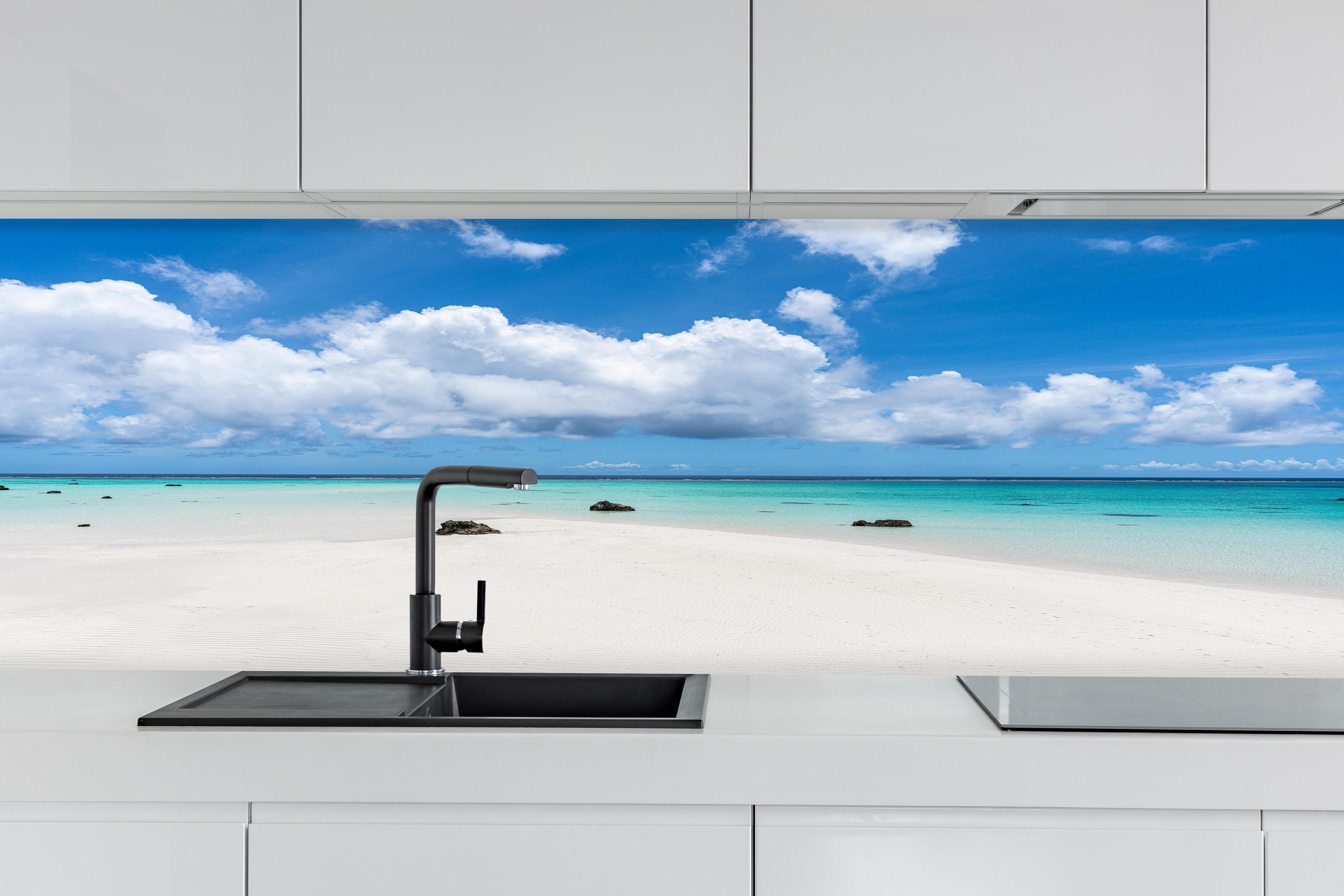 Küche - Idyllischer tropischer Strand mit kristallklarem Wasser und Wolkenhimmel hinter weißen Hochglanz-Küchenregalen und schwarzem Wasserhahn
