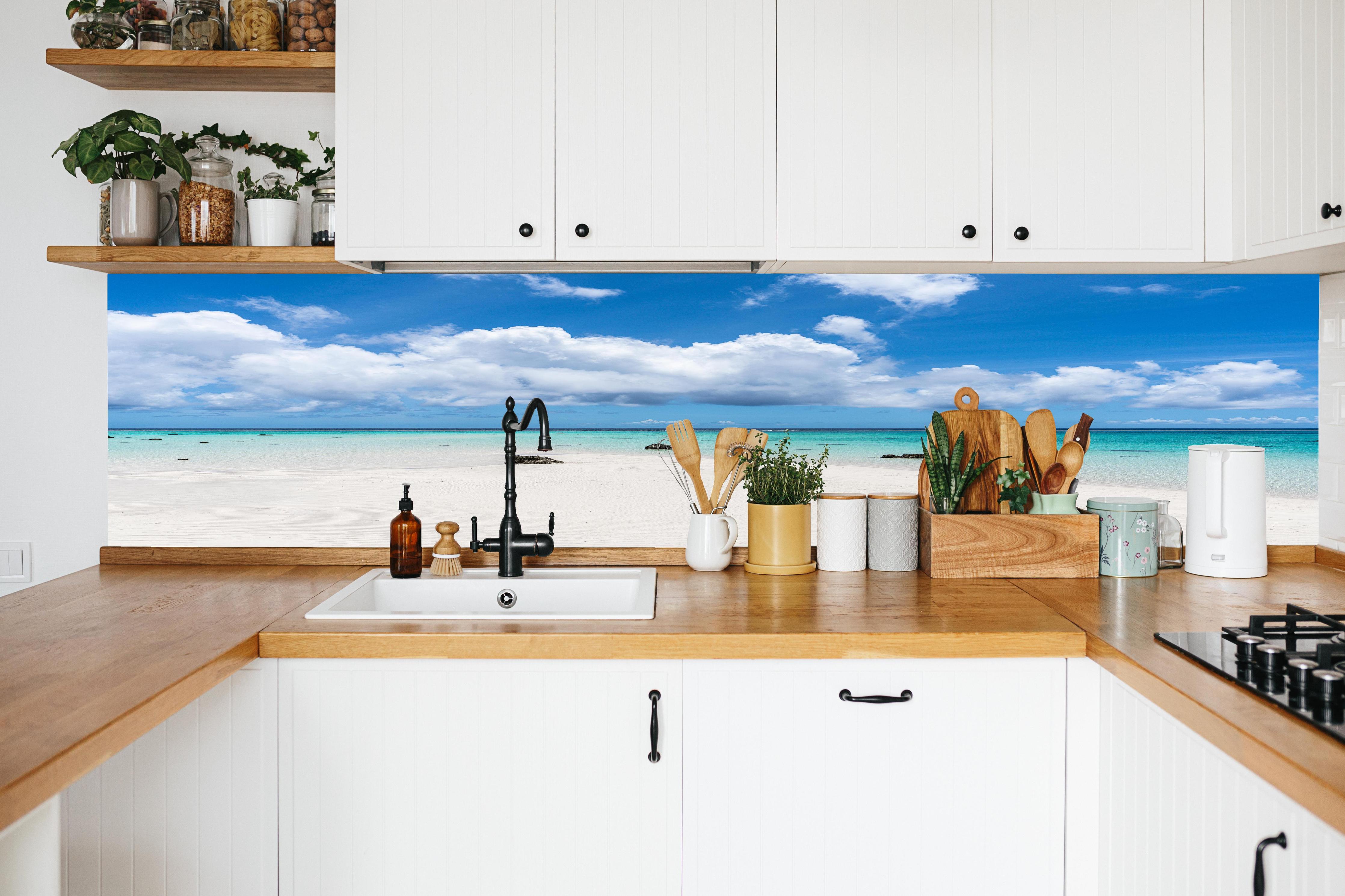 Küche - Idyllischer tropischer Strand mit kristallklarem Wasser und Wolkenhimmel hinter weißen Hochglanz-Küchenregalen und schwarzem Wasserhahn