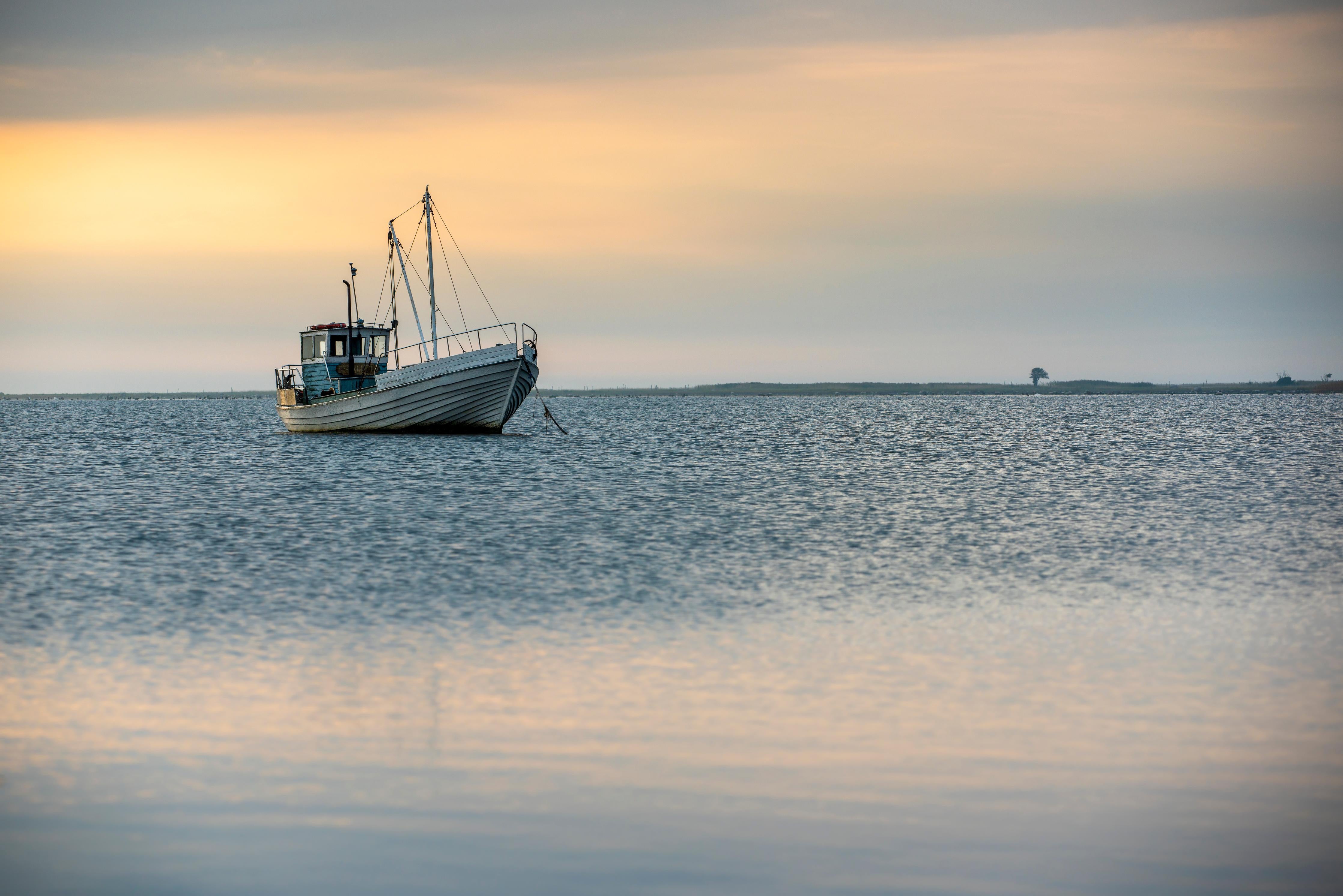Küchenrückwand-Idyllisches Boot auf ruhigem Wasser bei Sonnenuntergang
