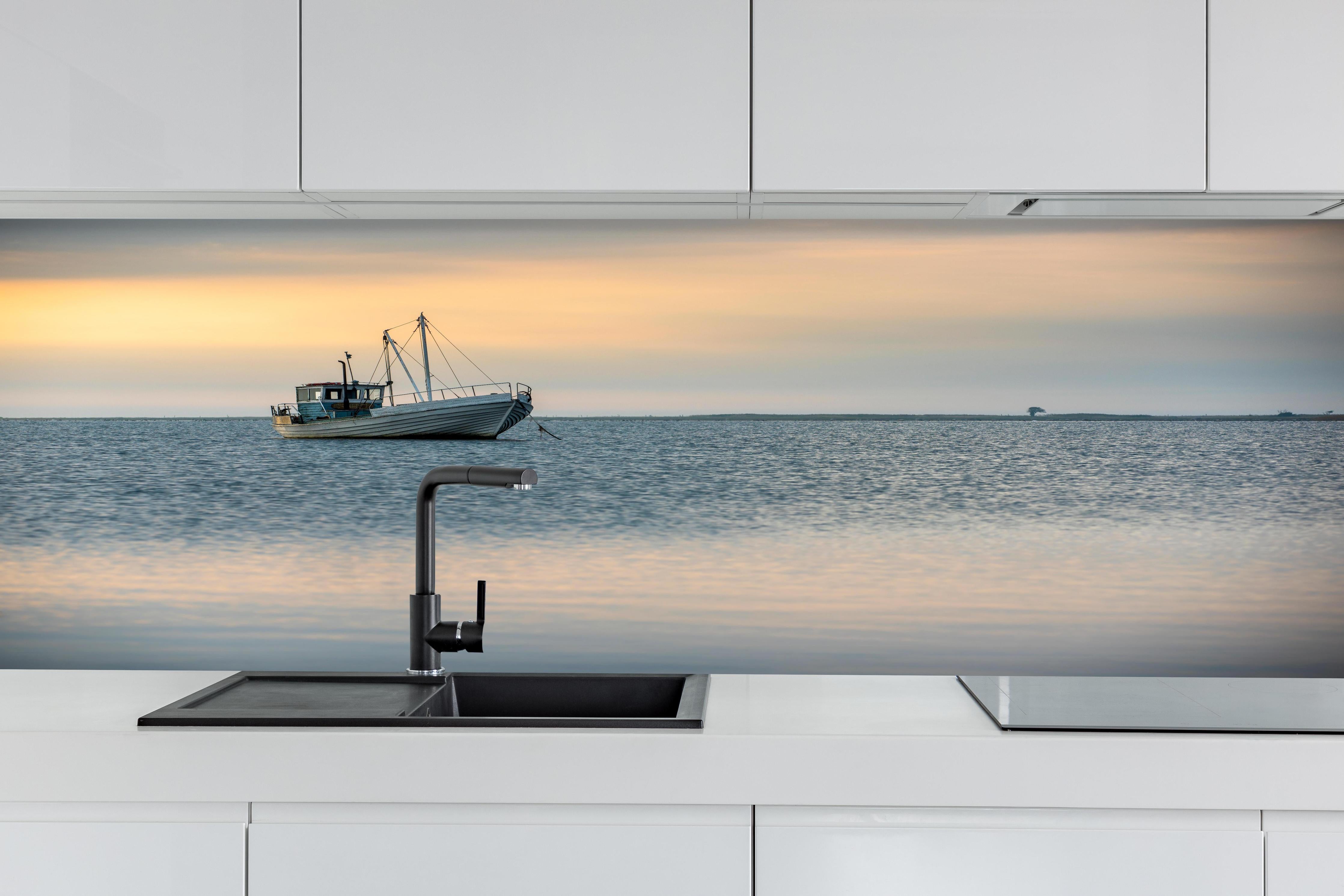 Küche - Idyllisches Boot auf ruhigem Wasser bei Sonnenuntergang hinter weißen Hochglanz-Küchenregalen und schwarzem Wasserhahn