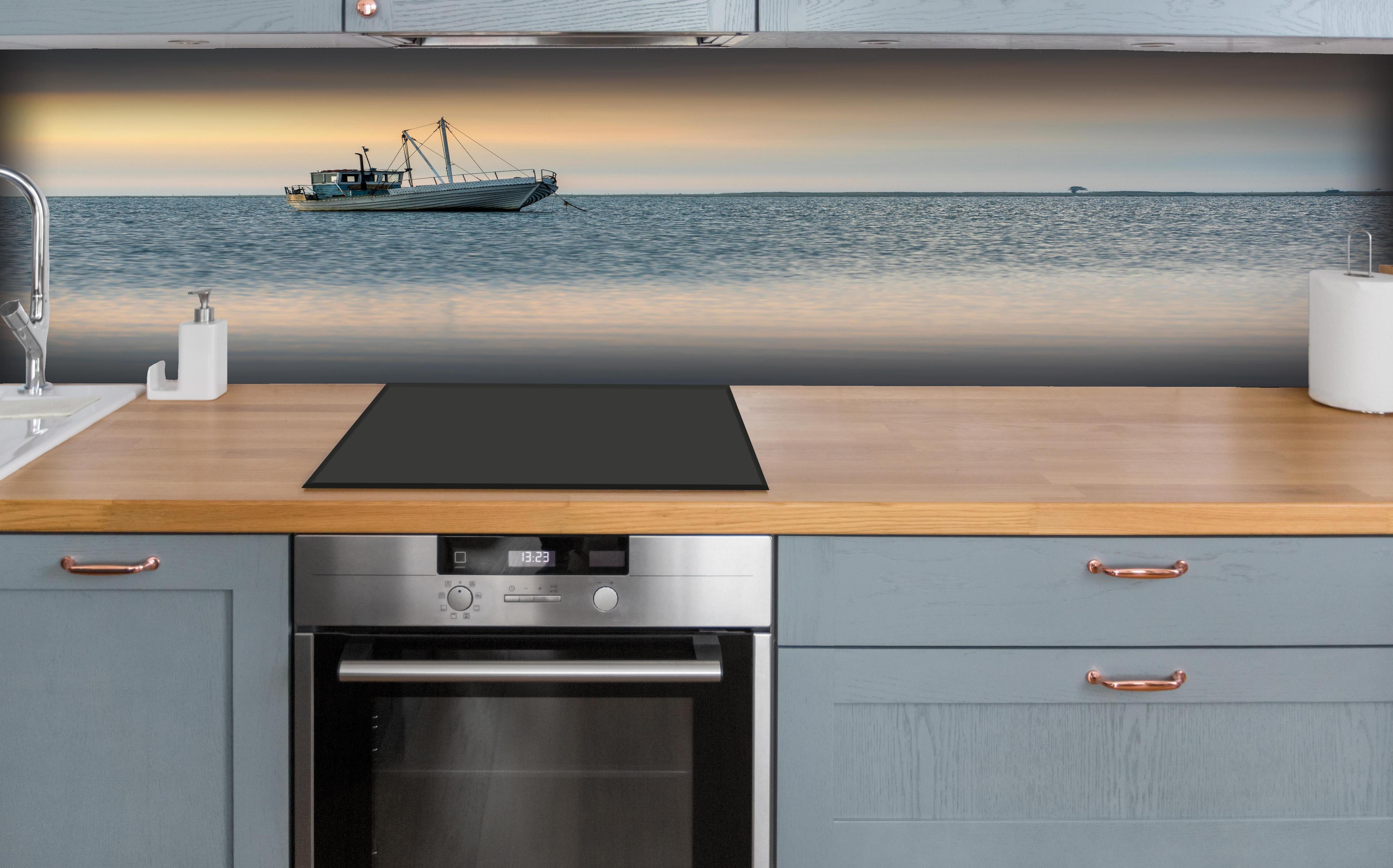 Küche - Idyllisches Boot auf ruhigem Wasser bei Sonnenuntergang hinter weißen Hochglanz-Küchenregalen und schwarzem Wasserhahn