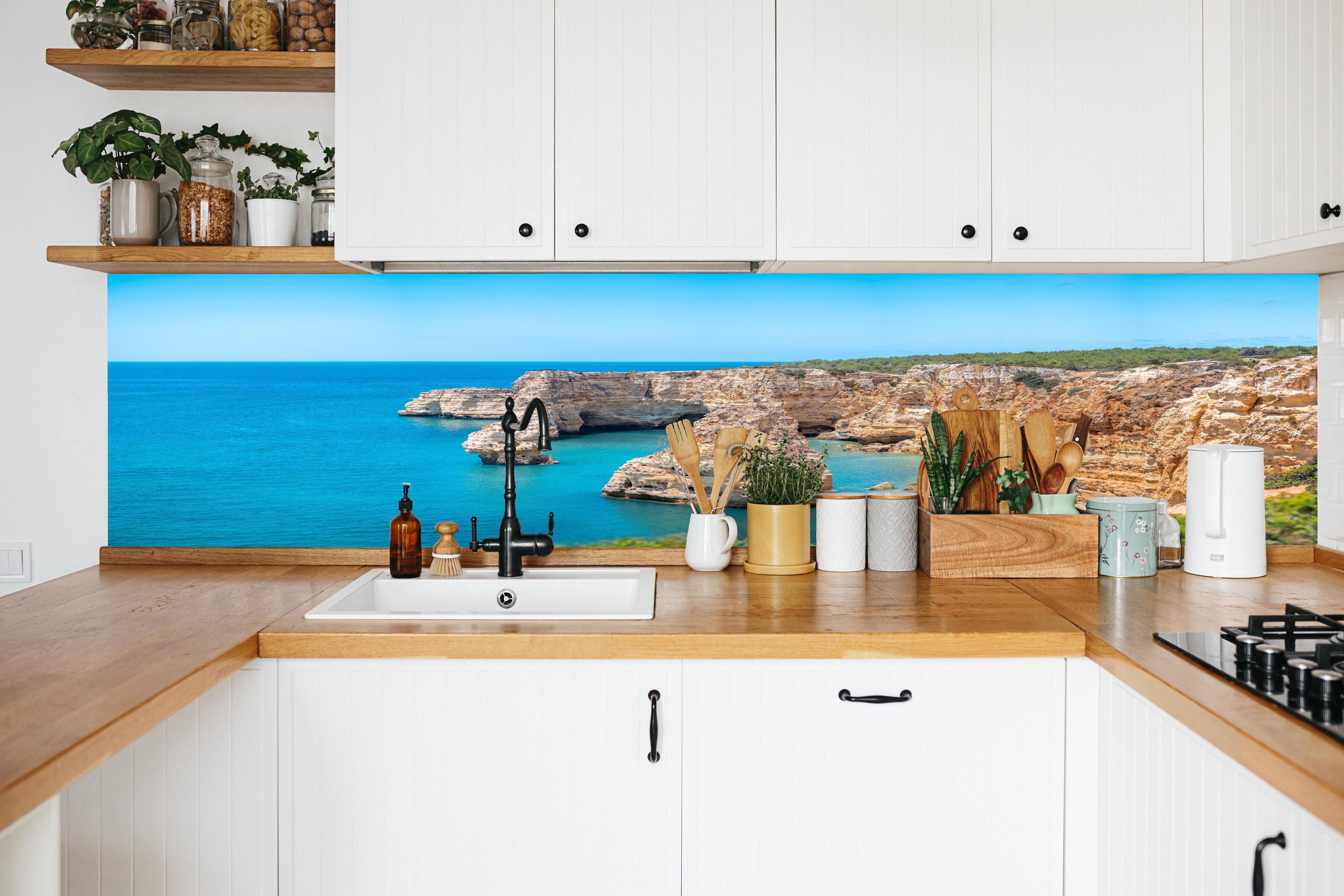 Küche - Algarve-Klippen am türkisblauen Meer in weißer Küche hinter Gewürzen und Kochlöffeln aus Holz