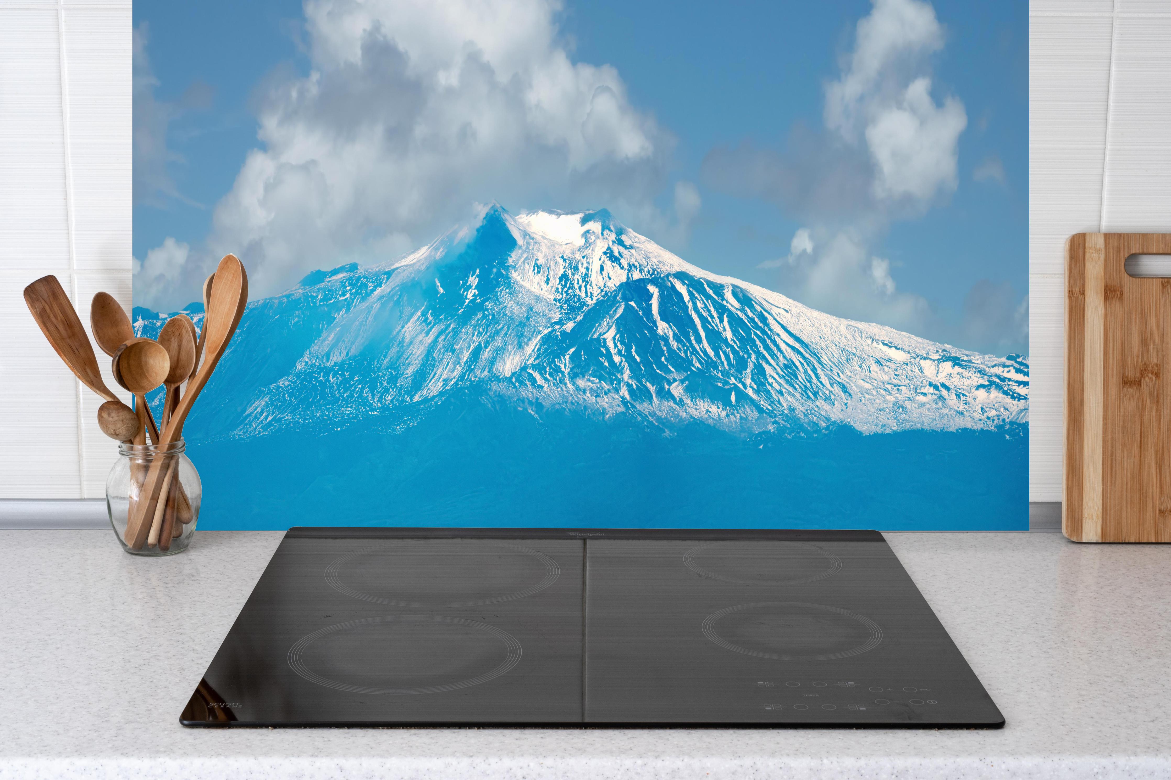 Küche - Blaue Schnee-Berglandschaft hinter Cerankochfeld und Holz-Kochutensilien