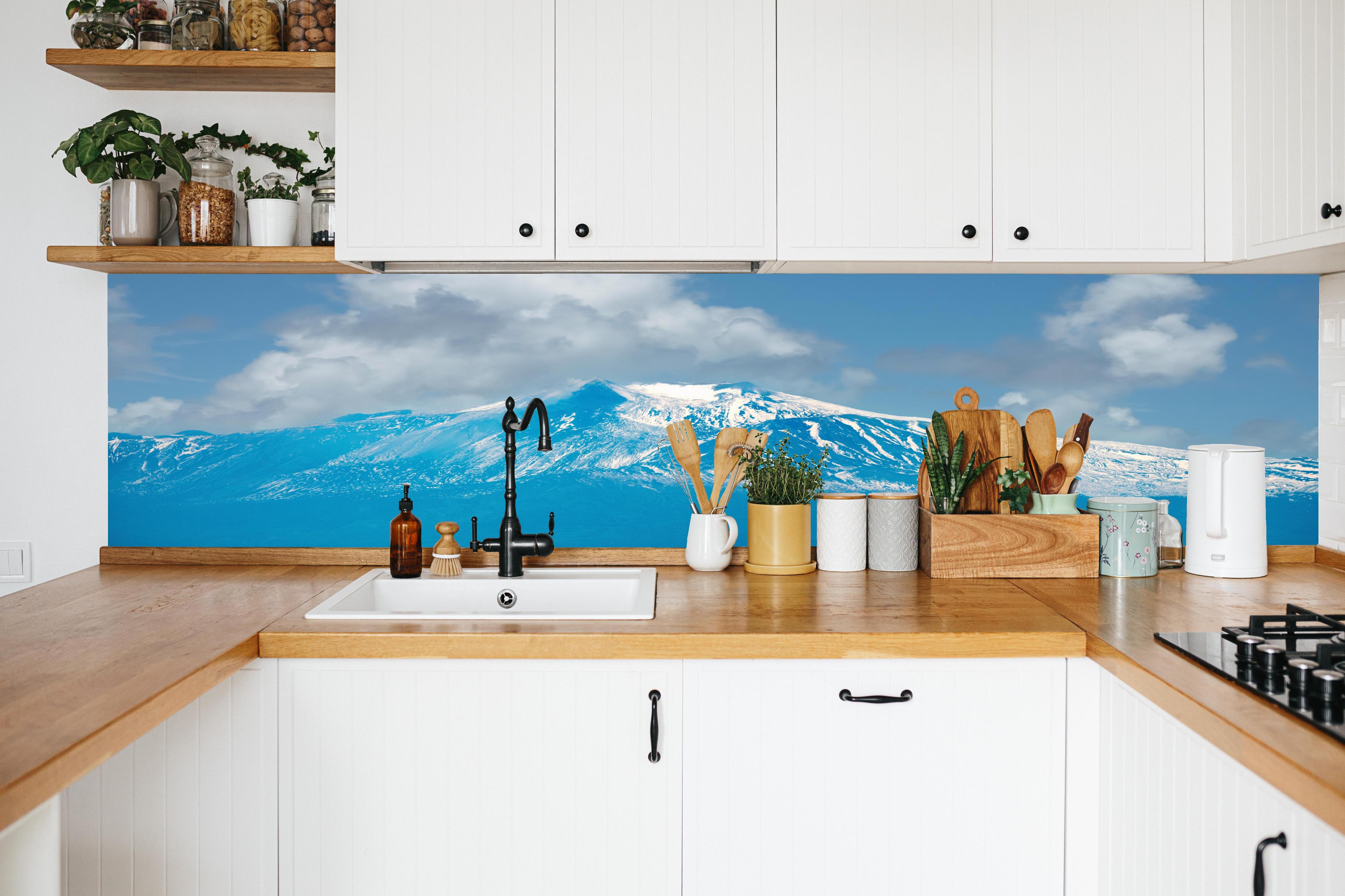 Küche - Blaue Schnee-Berglandschaft in weißer Küche hinter Gewürzen und Kochlöffeln aus Holz