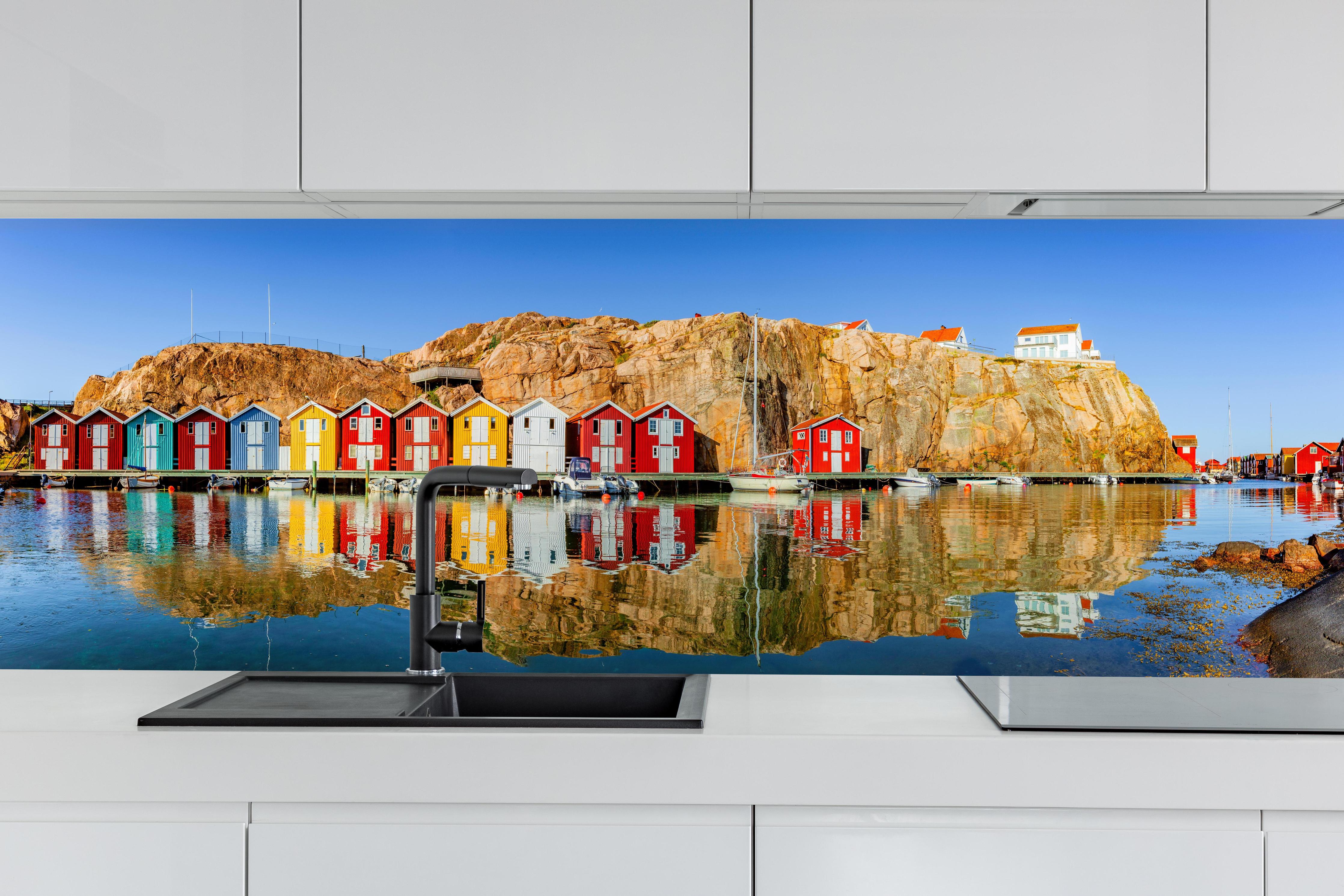 Küche - Bunte Fischerhäuser in Schweden hinter weißen Hochglanz-Küchenregalen und schwarzem Wasserhahn