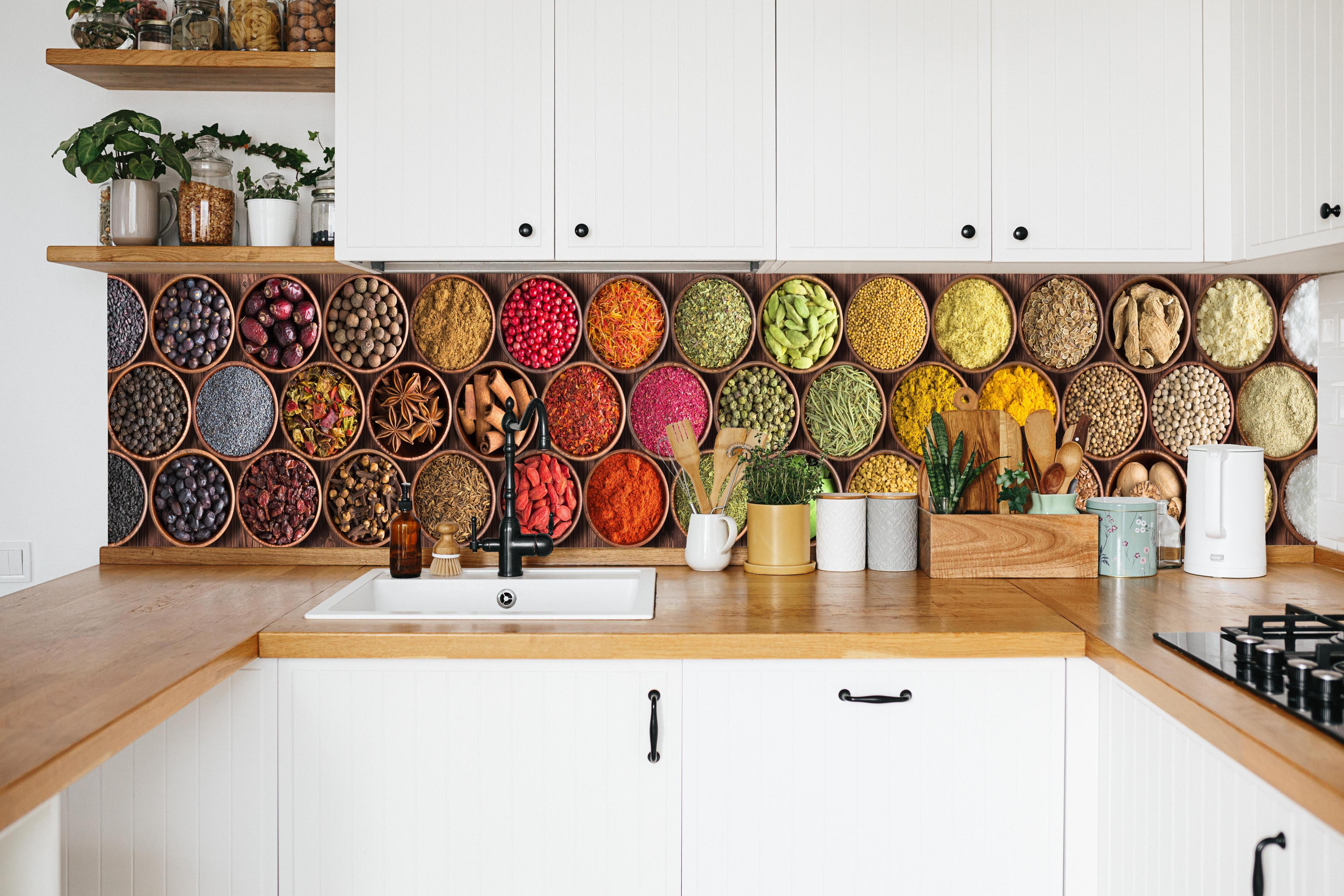 Küche - Bunte Gewürzschalen in weißer Küche hinter Gewürzen und Kochlöffeln aus Holz