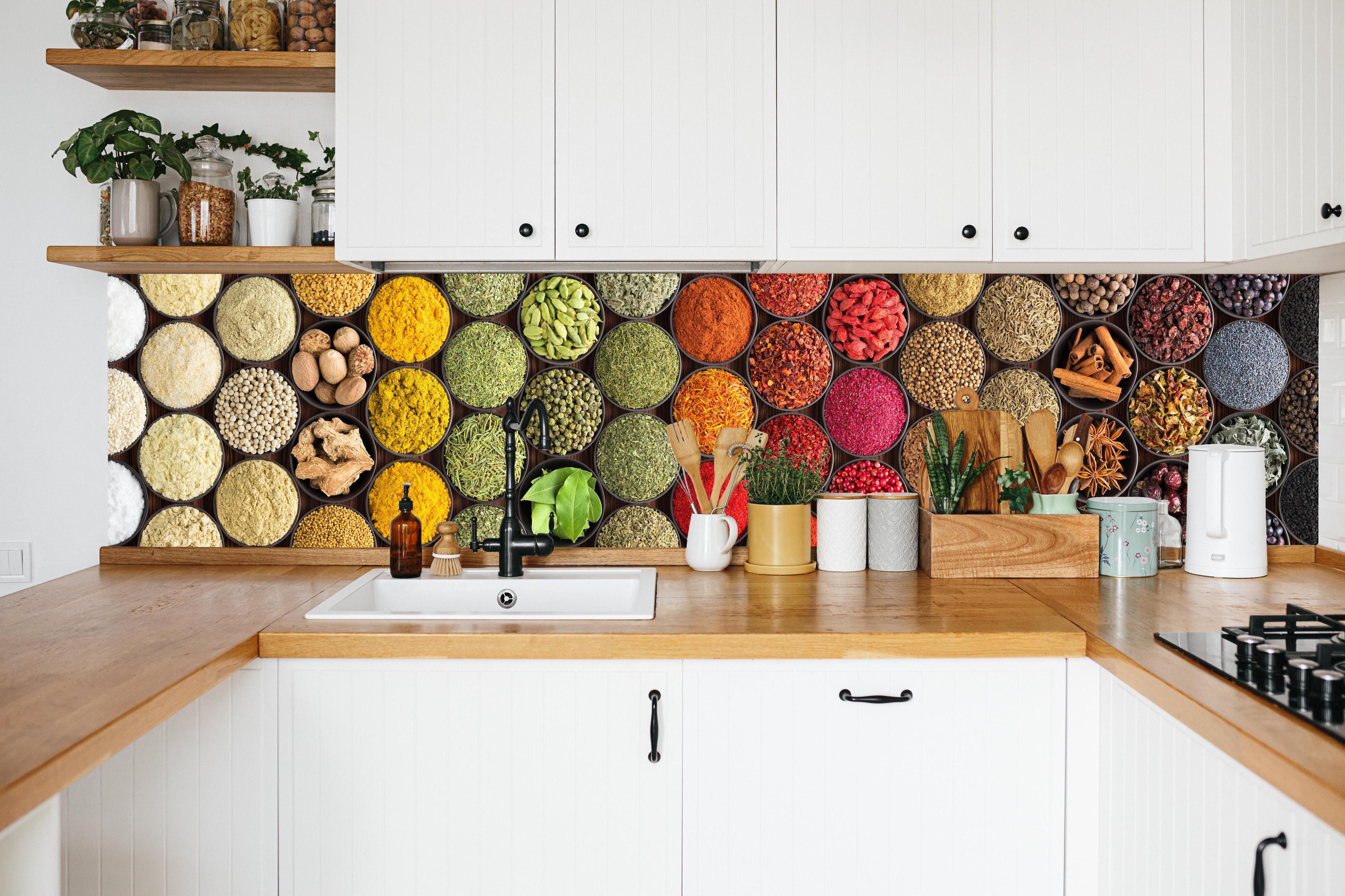 Küche - Buntes Gewürz-Mosaik in weißer Küche hinter Gewürzen und Kochlöffeln aus Holz