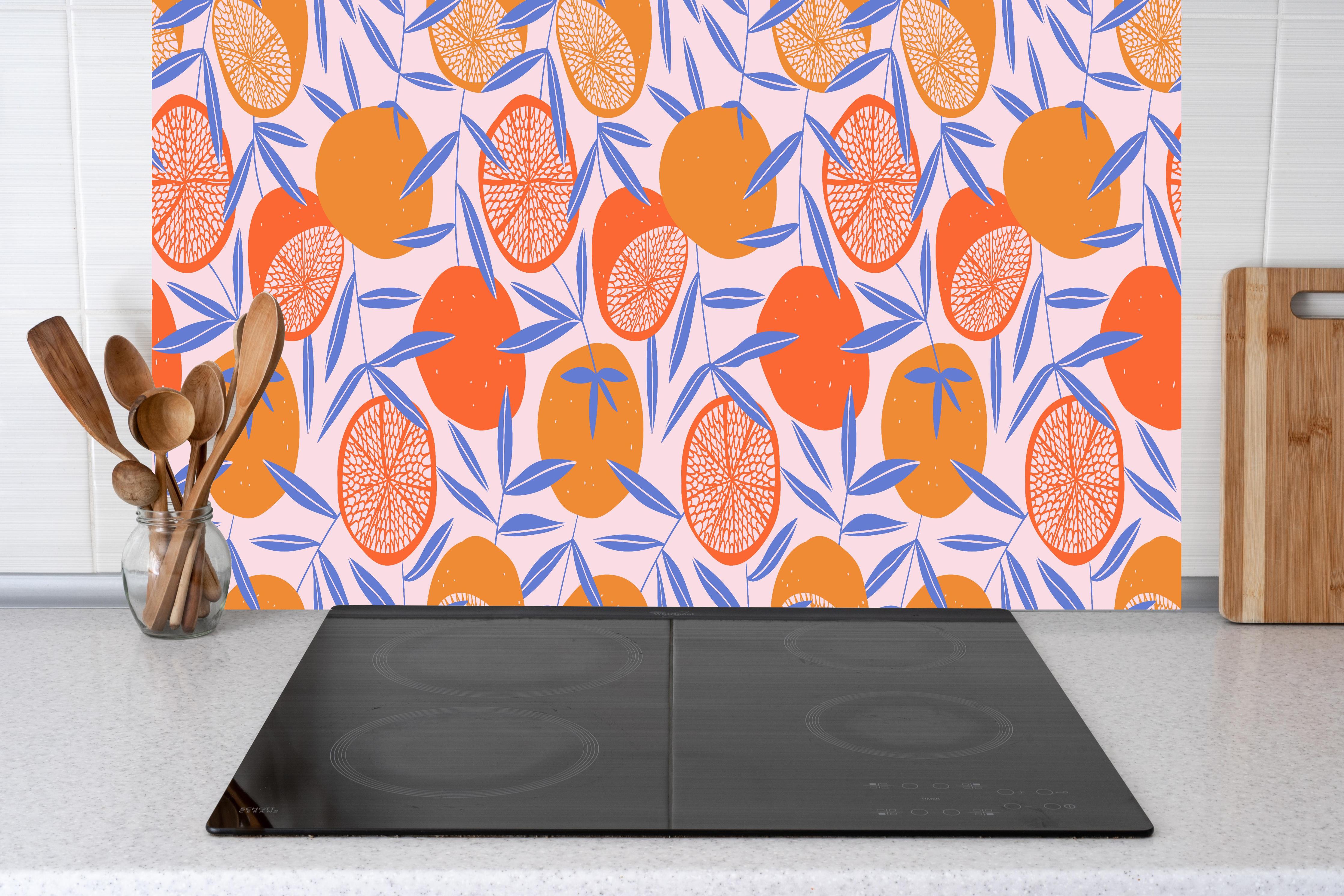 Küche - Citrus Orange Print hinter Cerankochfeld und Holz-Kochutensilien