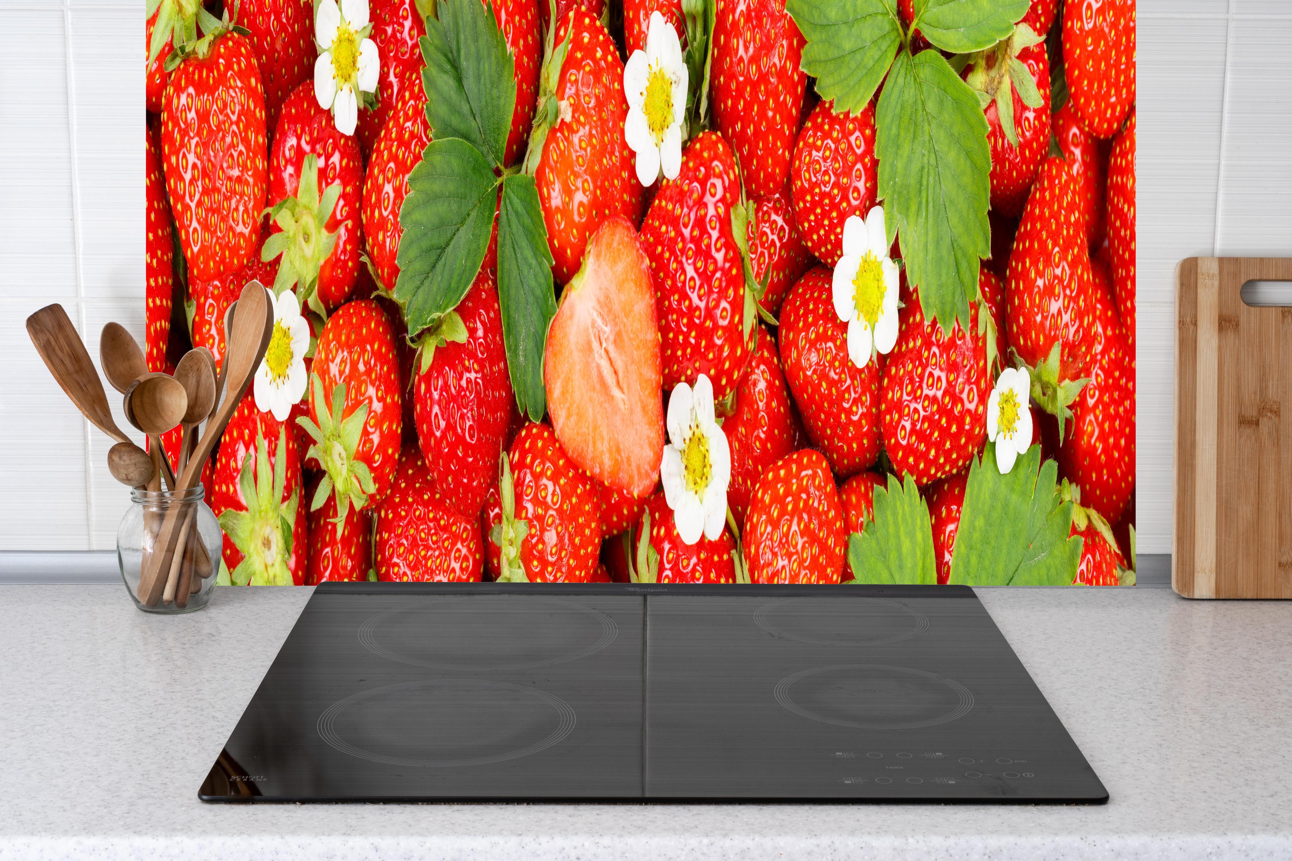 Küche - Frische rote Erdbeeren hinter Cerankochfeld und Holz-Kochutensilien