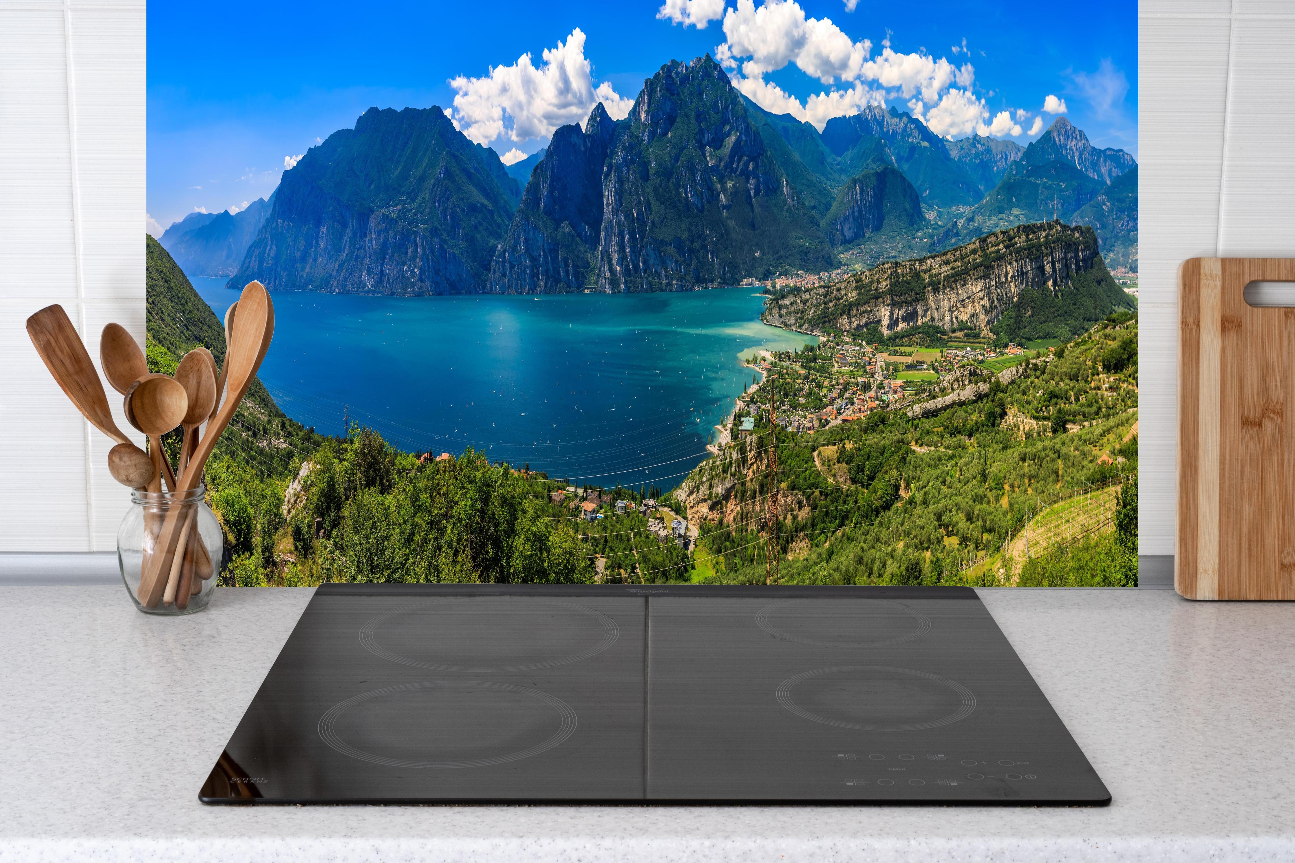 Küche - Gardasee Panorama in Blau und Grün hinter Cerankochfeld und Holz-Kochutensilien