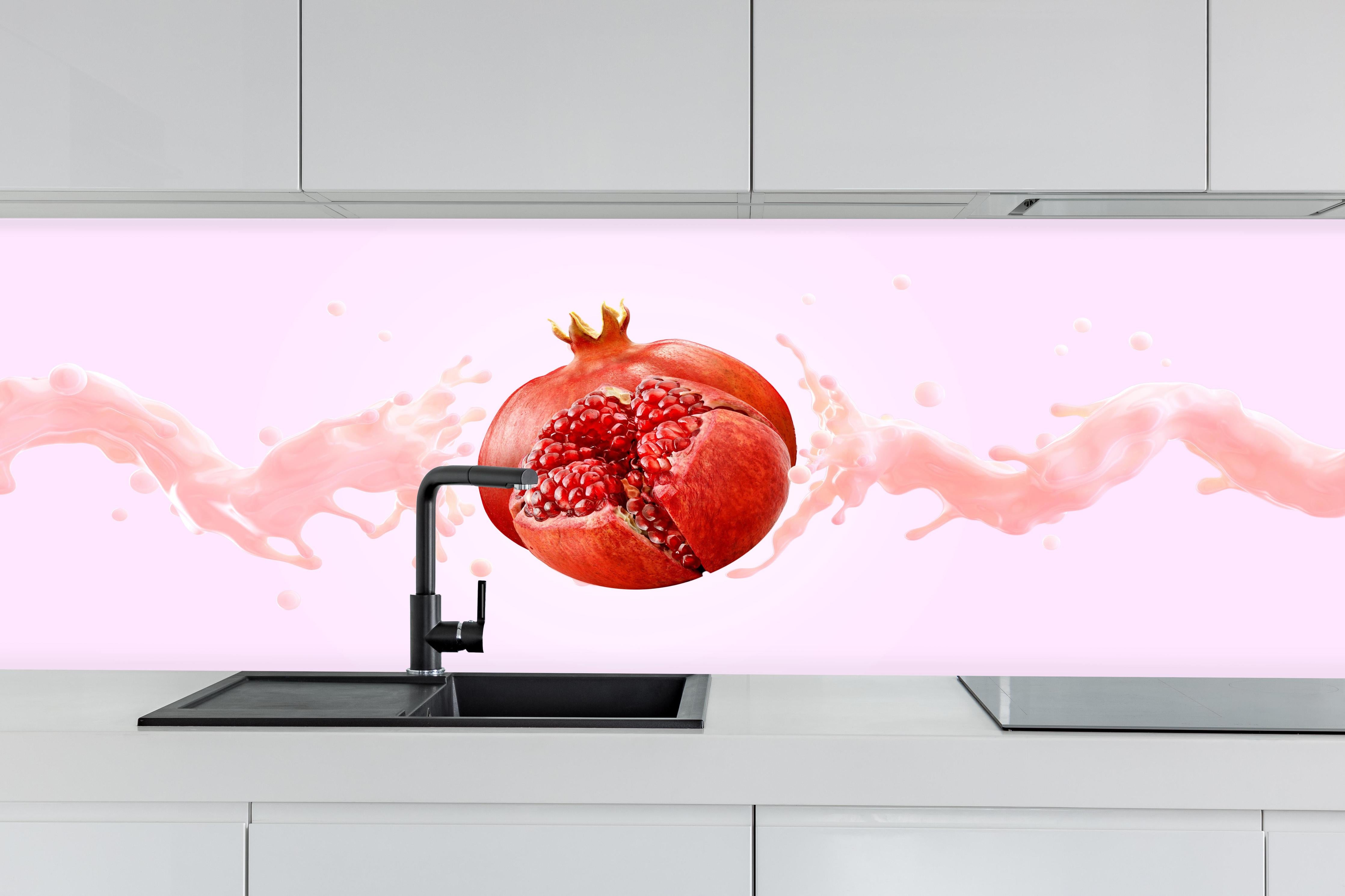Küche - Granatapfel mit rosa Milch-Splash hinter weißen Hochglanz-Küchenregalen und schwarzem Wasserhahn