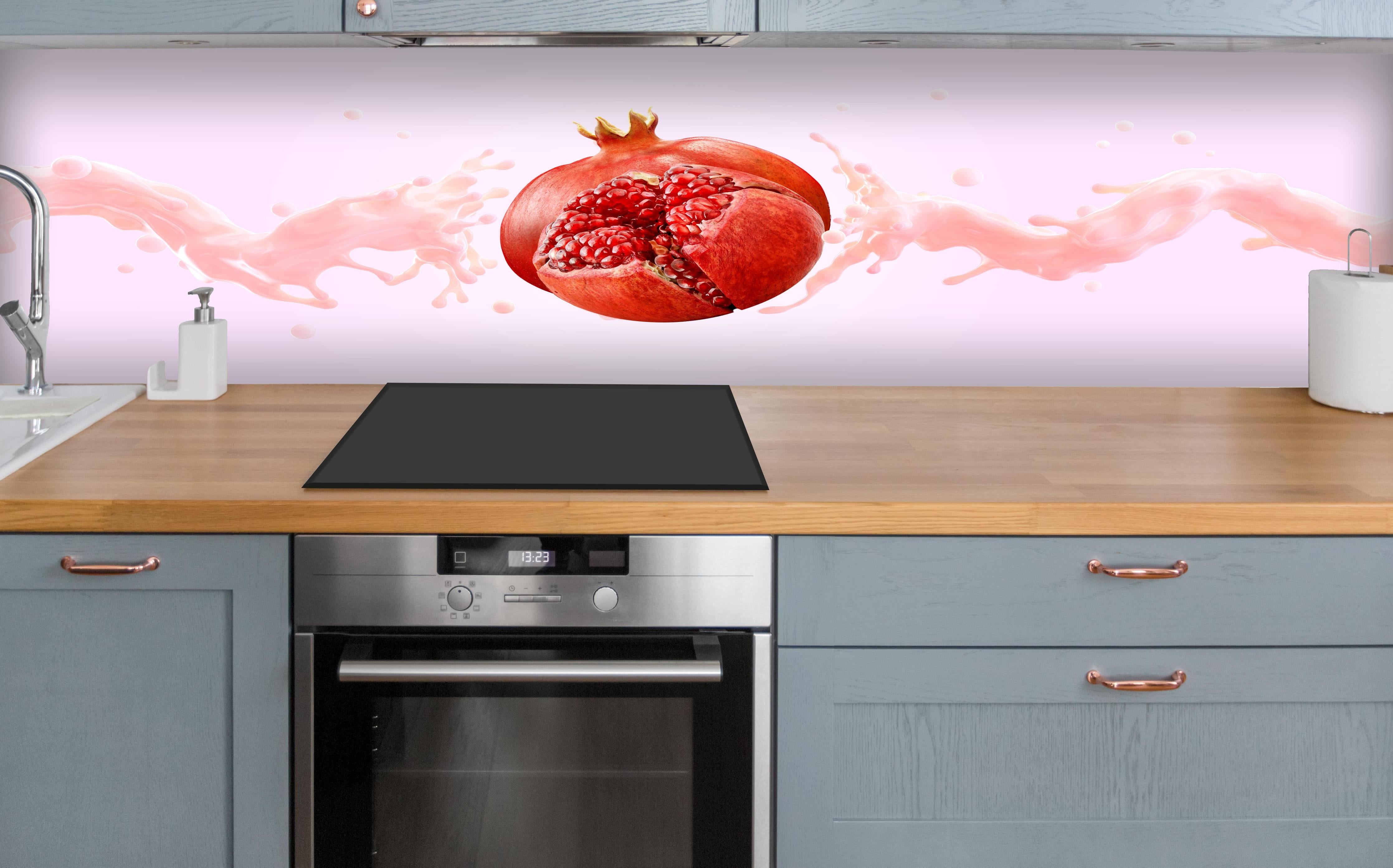 Küche - Granatapfel mit rosa Milch-Splash über polierter Holzarbeitsplatte mit Cerankochfeld