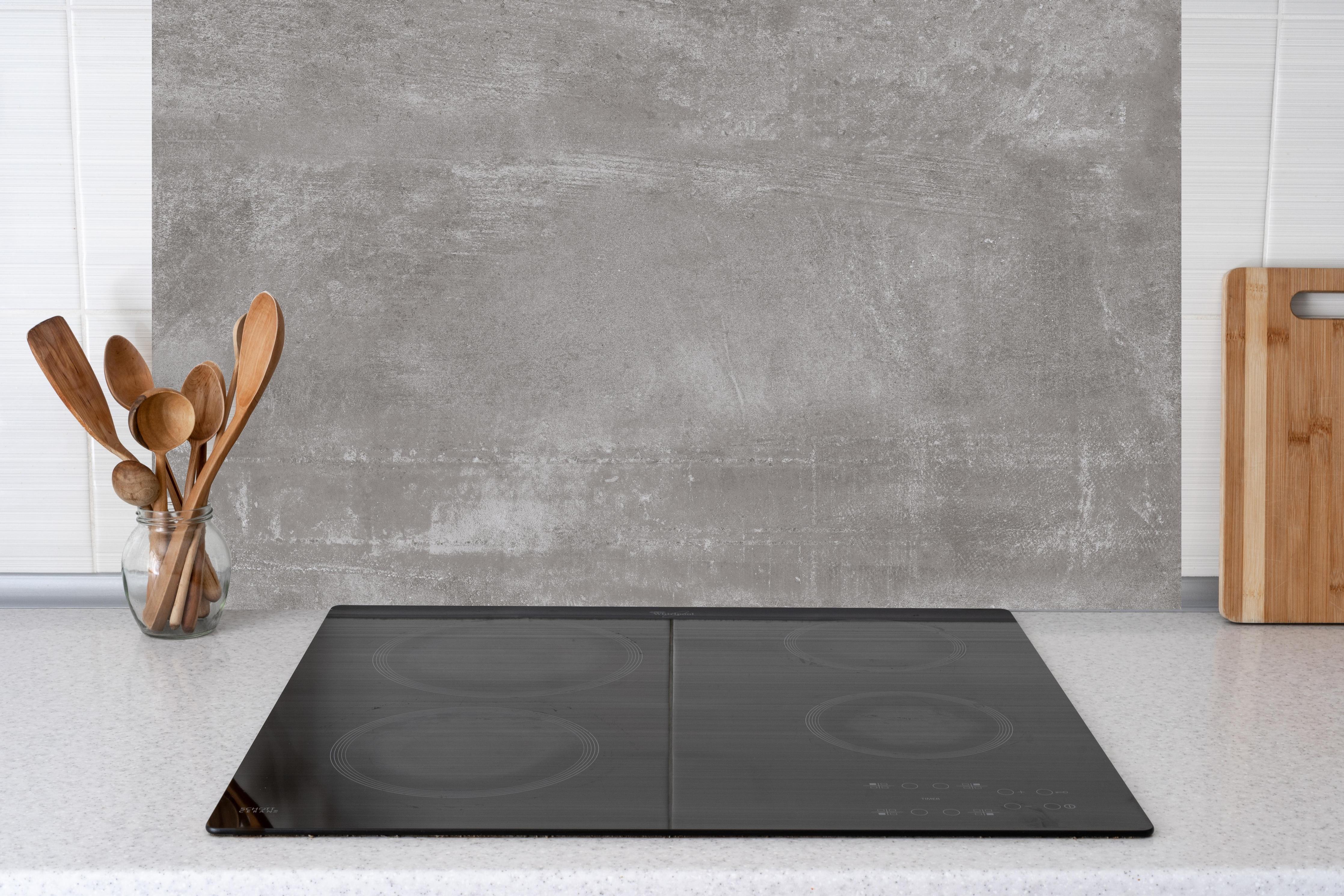 Küche - Graue Beton-Textur hinter Cerankochfeld und Holz-Kochutensilien