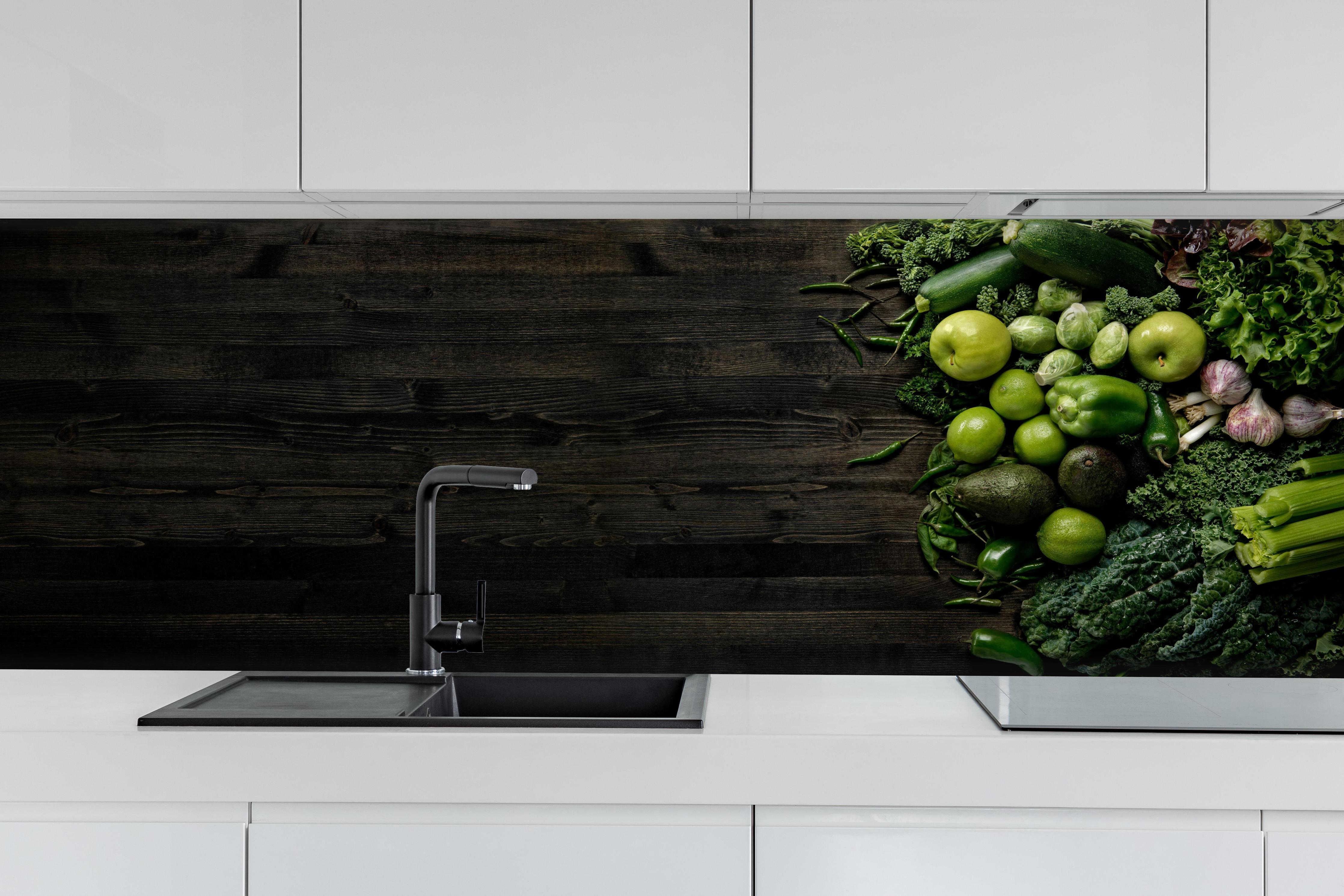 Küche - Grünes Gemüse auf dunklem Holz hinter weißen Hochglanz-Küchenregalen und schwarzem Wasserhahn
