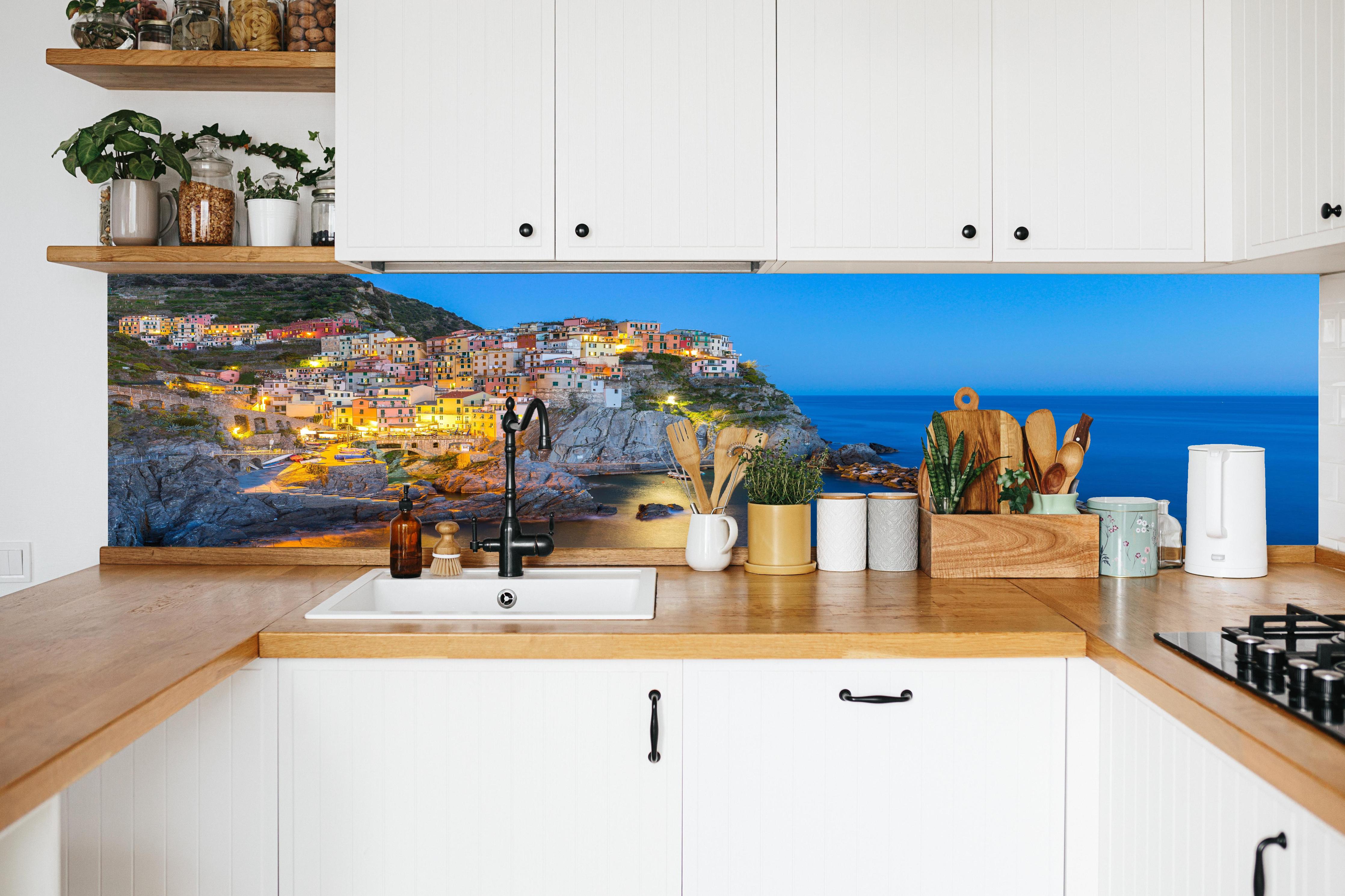 Küche - Italienische Küstenstadt bei Abendlicht in weißer Küche hinter Gewürzen und Kochlöffeln aus Holz