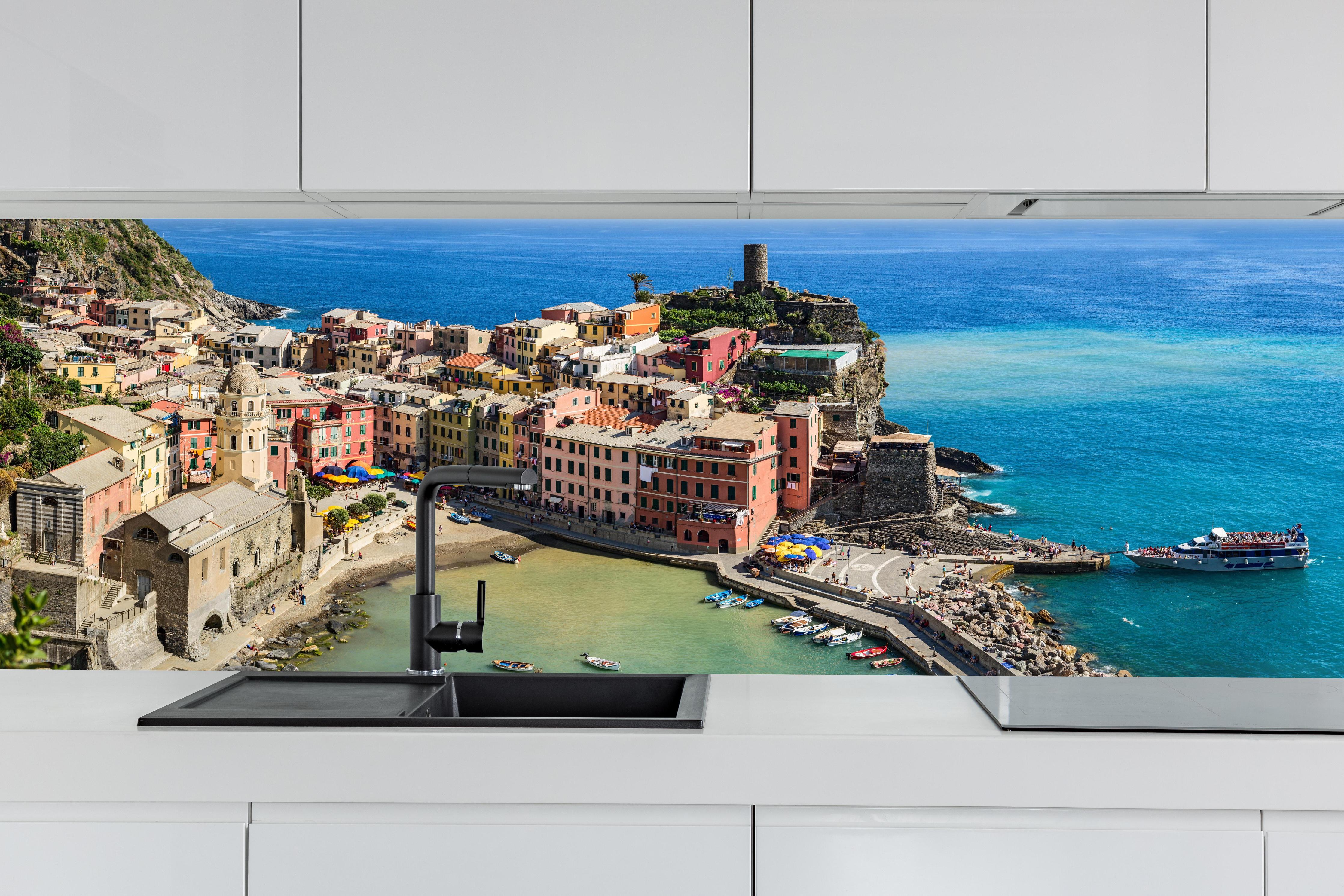 Küche - Italienische Küstenstadt in Türkis hinter weißen Hochglanz-Küchenregalen und schwarzem Wasserhahn