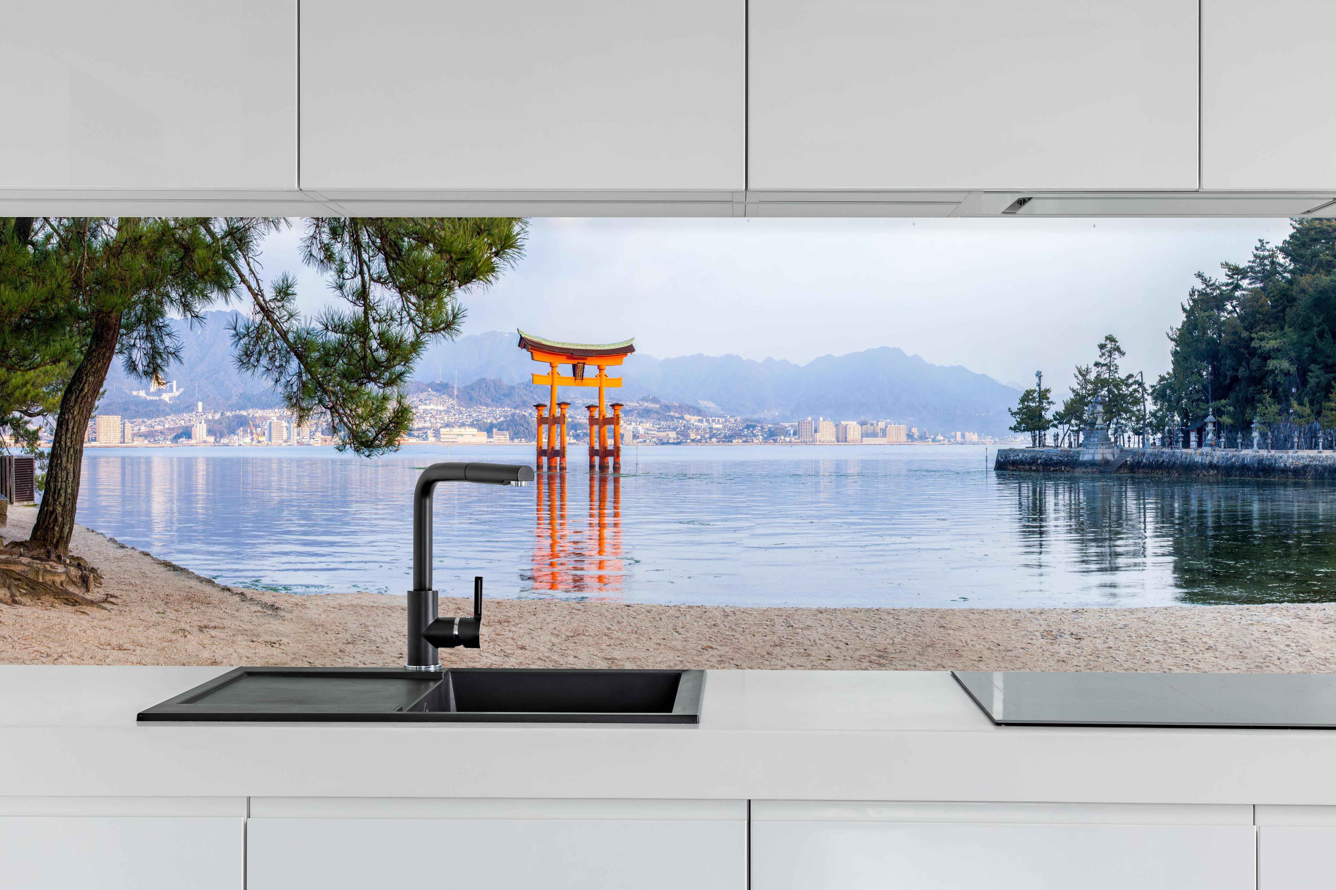 Küche - Japanisches Torii am Meer hinter weißen Hochglanz-Küchenregalen und schwarzem Wasserhahn