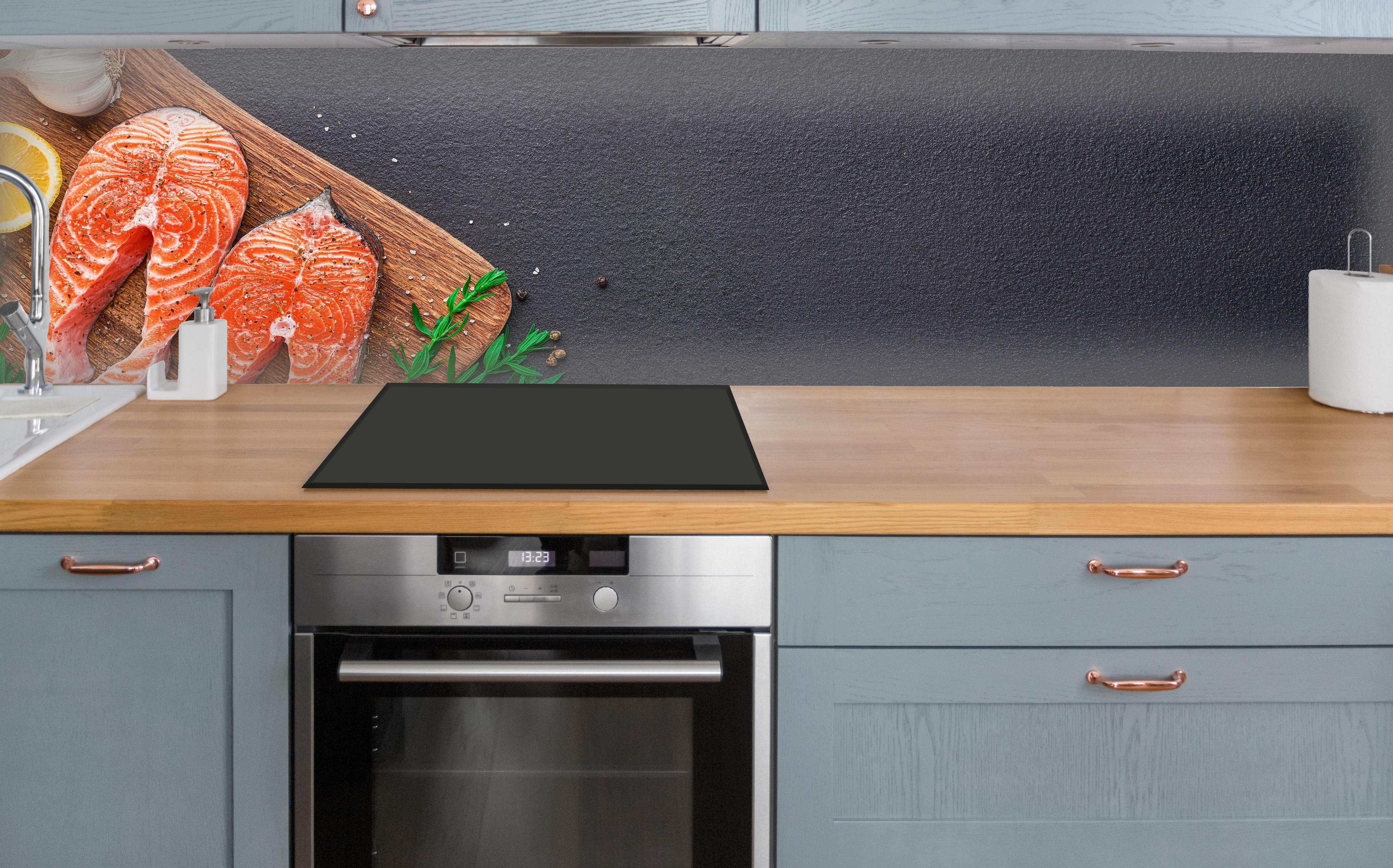 Küche - Lachssteaks auf Holzbrett über polierter Holzarbeitsplatte mit Cerankochfeld