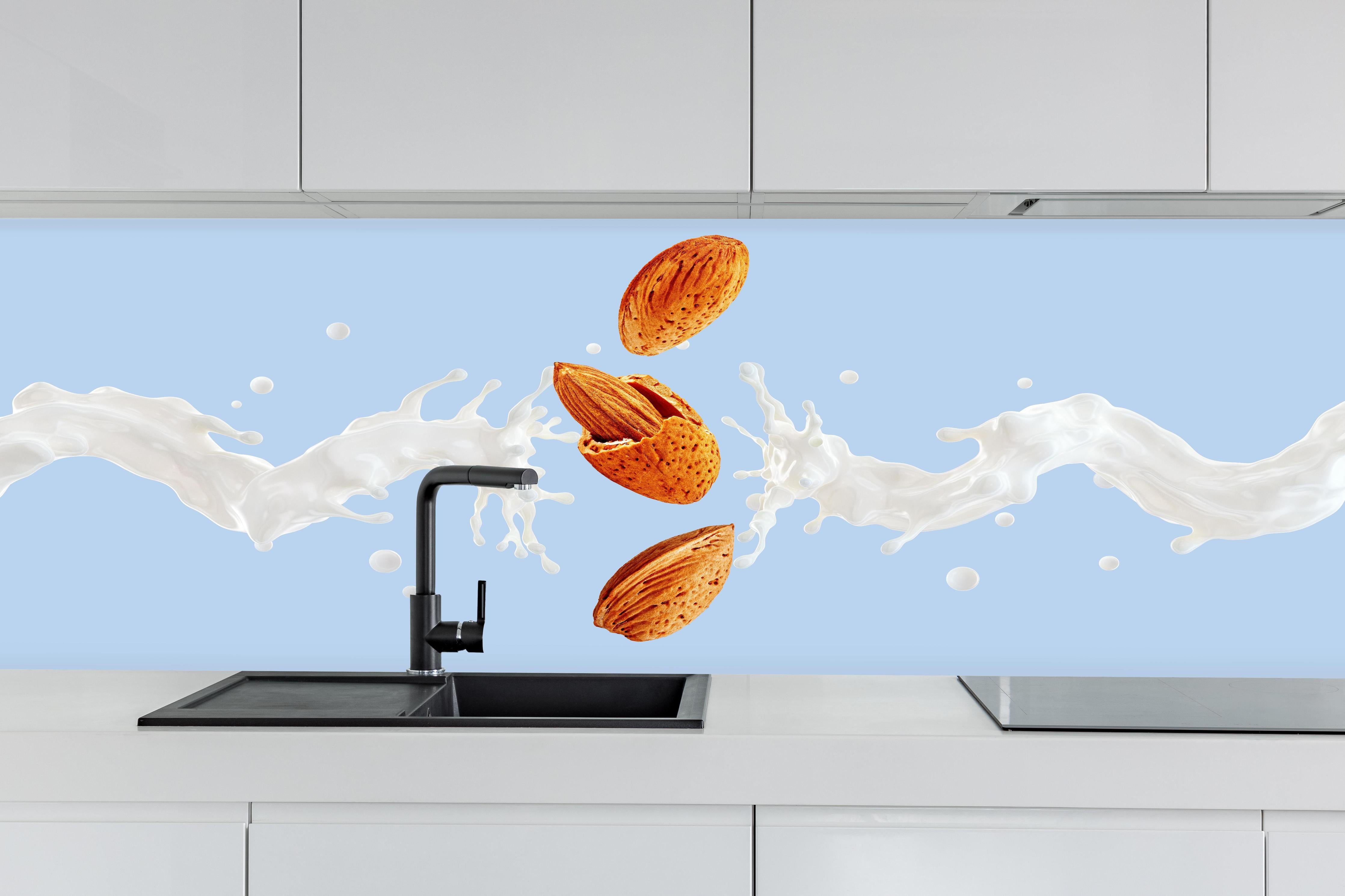 Küche - Mandelmilch-Splash auf Blau hinter weißen Hochglanz-Küchenregalen und schwarzem Wasserhahn
