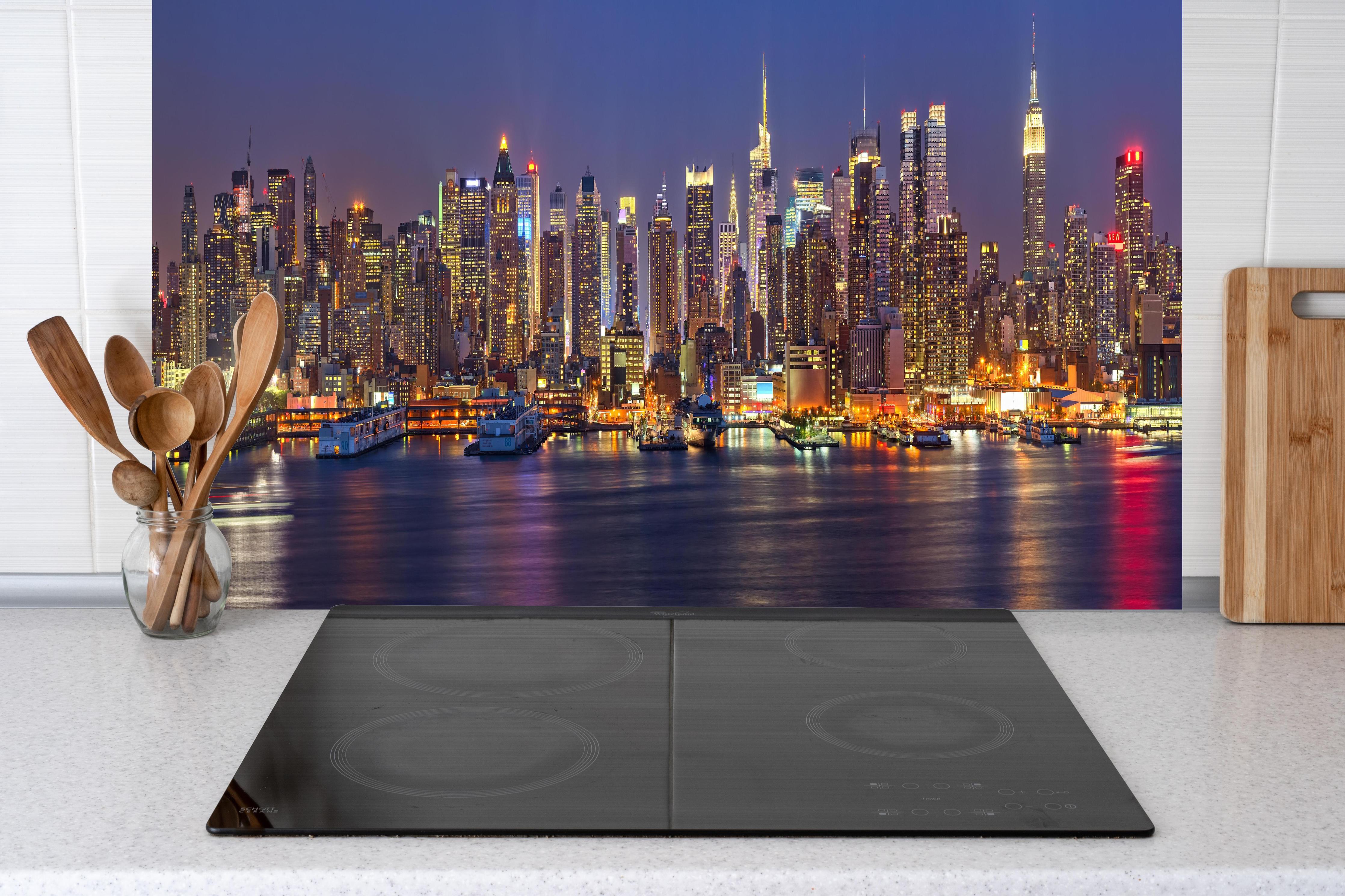Küche - Manhattan Skyline bei Nacht hinter Cerankochfeld und Holz-Kochutensilien