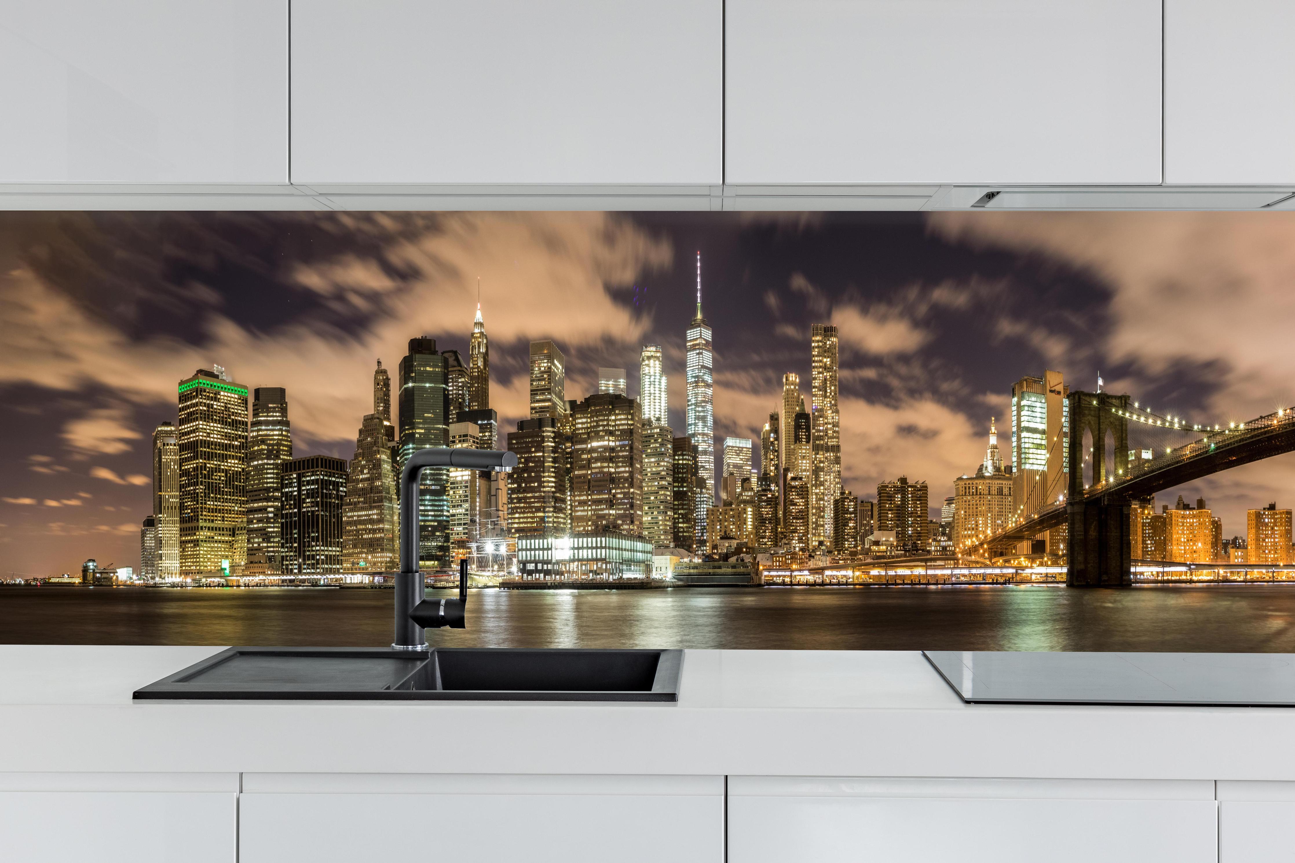 Küche - Manhattan Skyline im Glanz der Nacht hinter weißen Hochglanz-Küchenregalen und schwarzem Wasserhahn