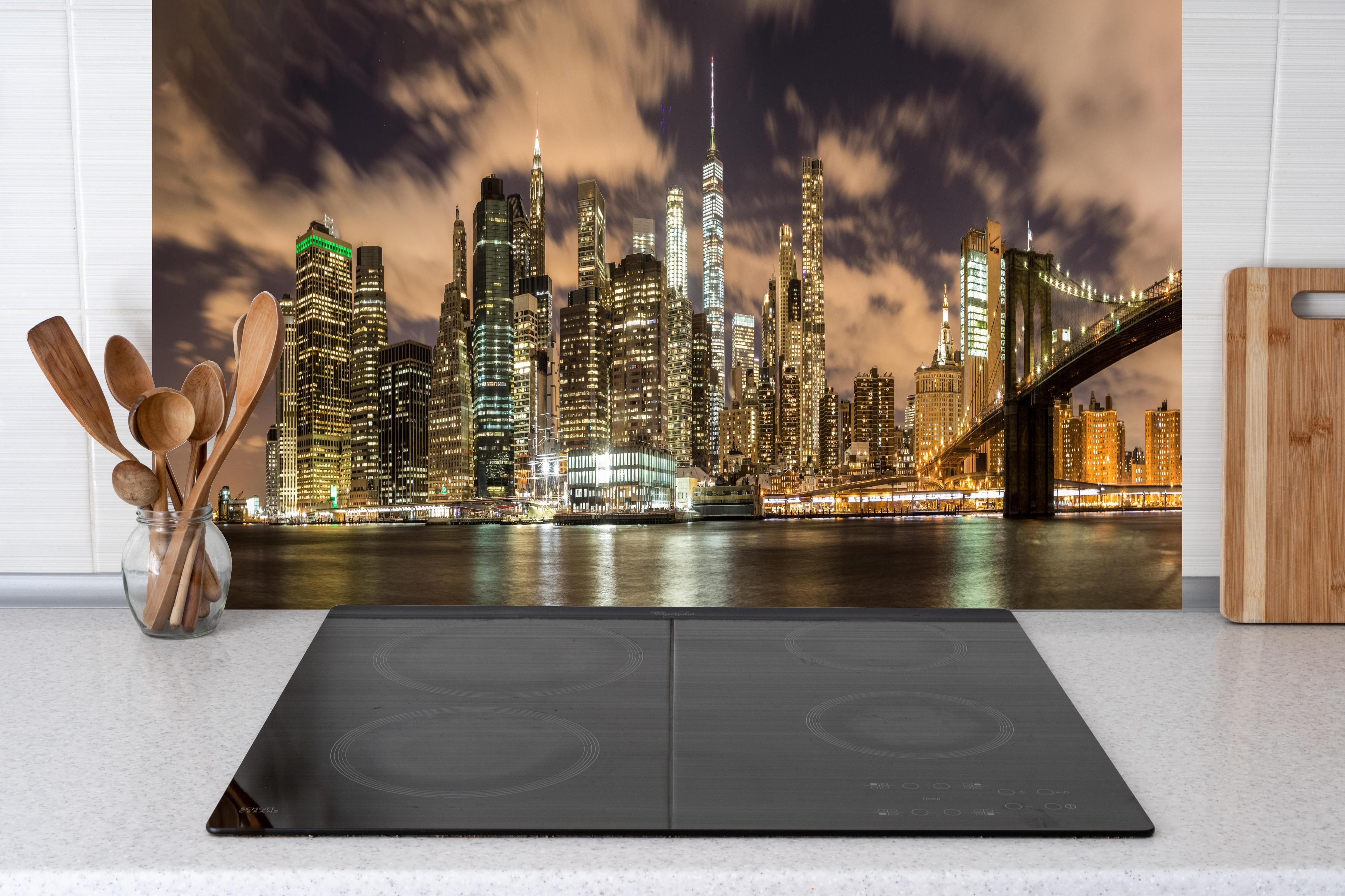 Küche - Manhattan Skyline im Glanz der Nacht hinter Cerankochfeld und Holz-Kochutensilien