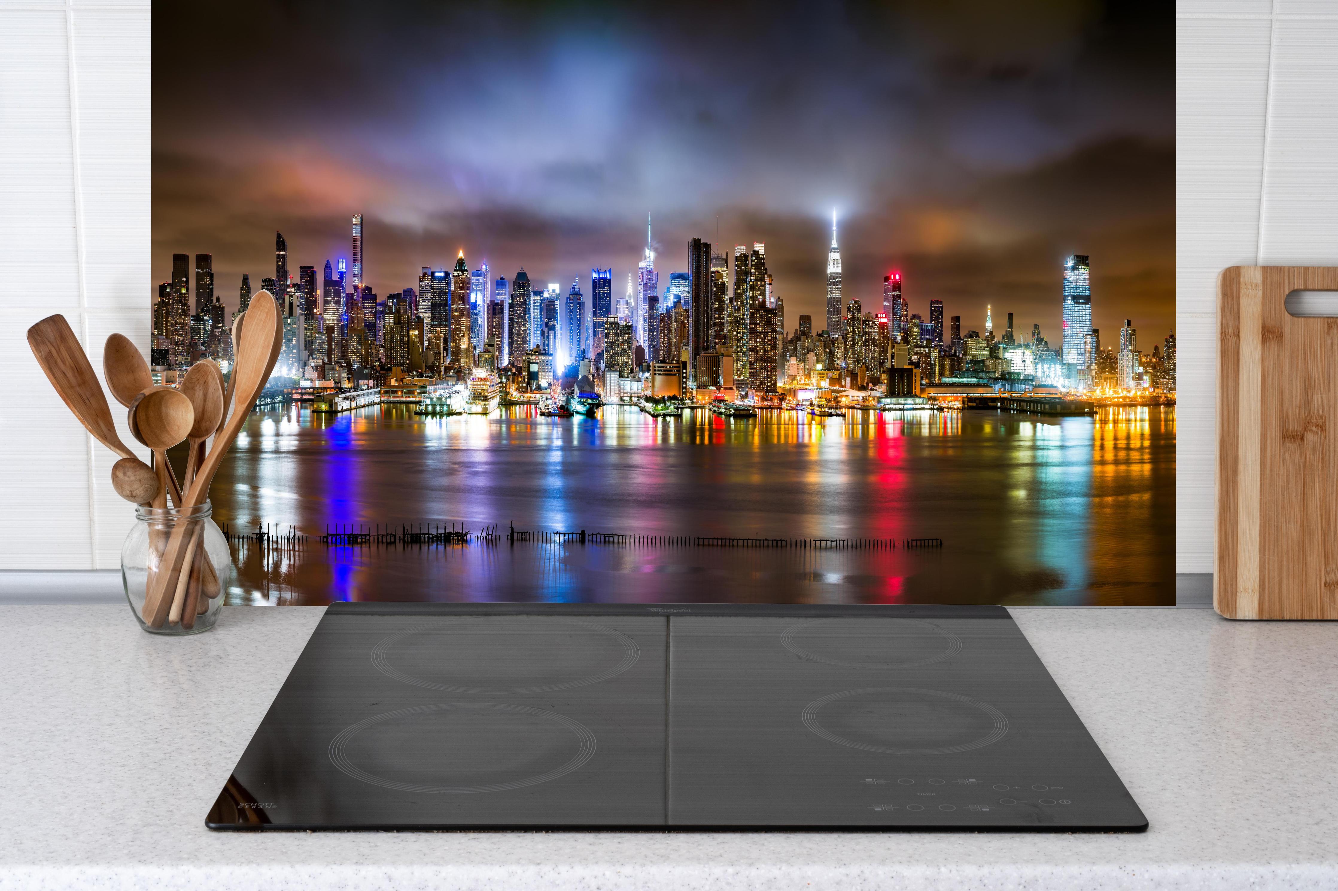 Küche - Manhattan Skyline im nächtlichen Panorama hinter Cerankochfeld und Holz-Kochutensilien