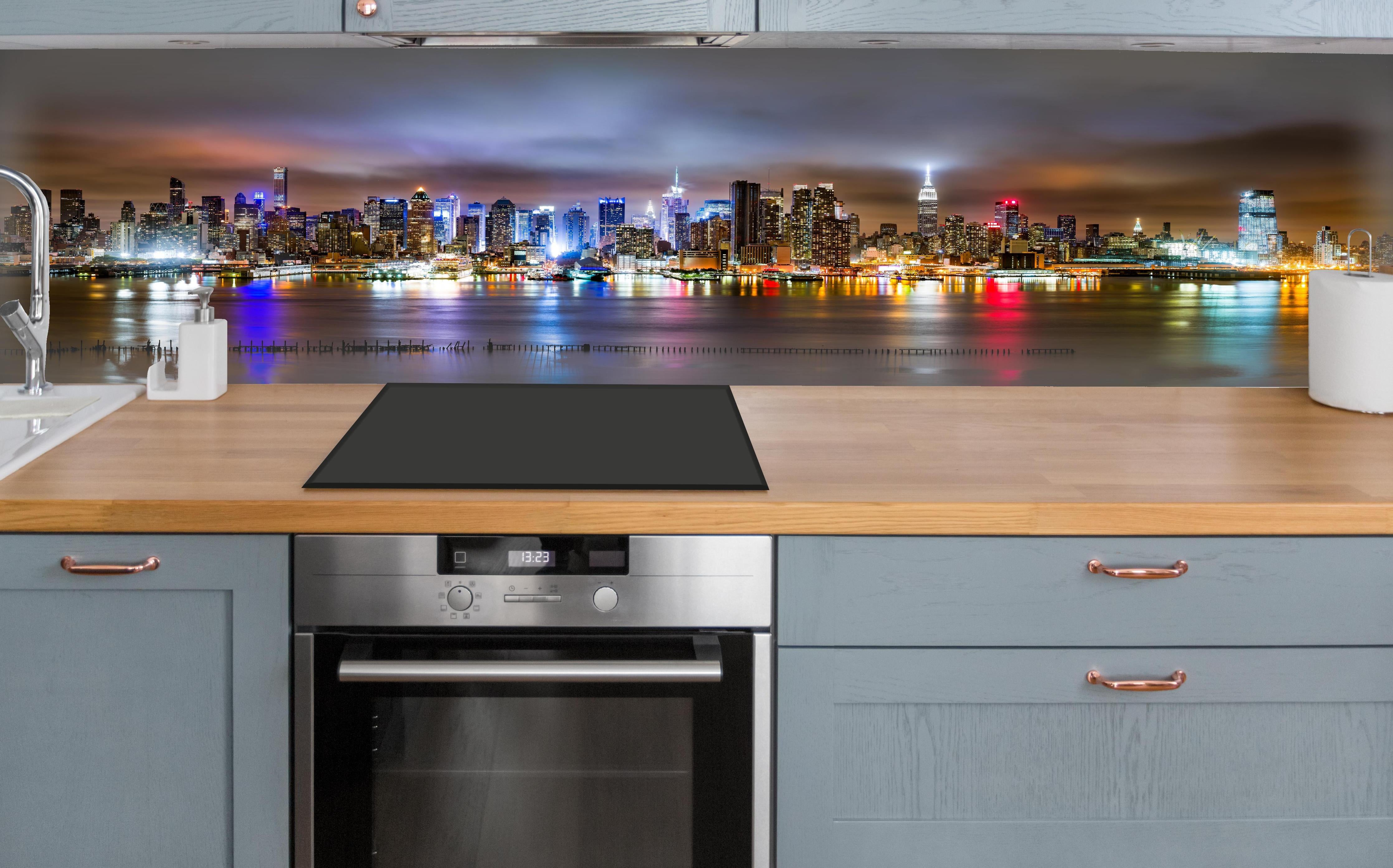 Küche - Manhattan Skyline im nächtlichen Panorama über polierter Holzarbeitsplatte mit Cerankochfeld