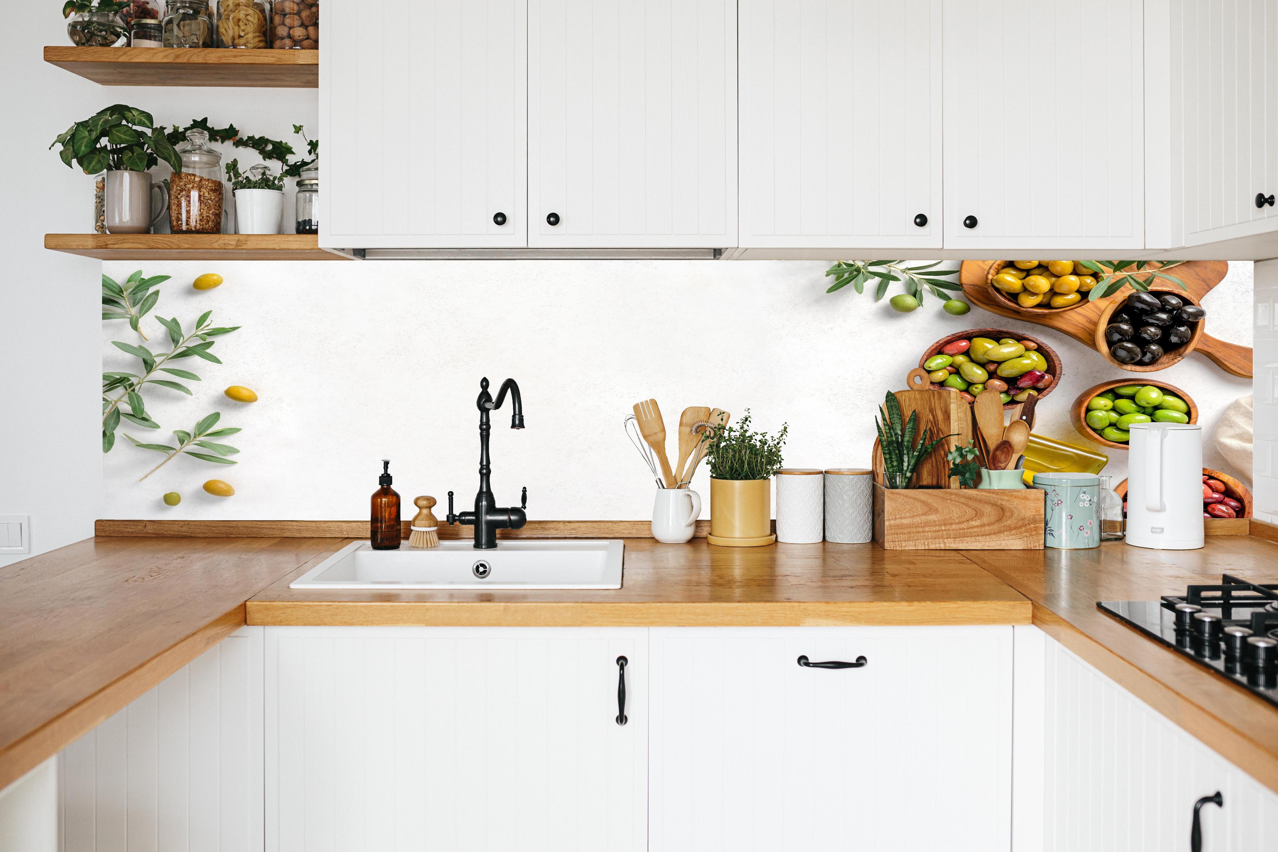 Küche - Mediterrane Oliven auf Weiß in weißer Küche hinter Gewürzen und Kochlöffeln aus Holz
