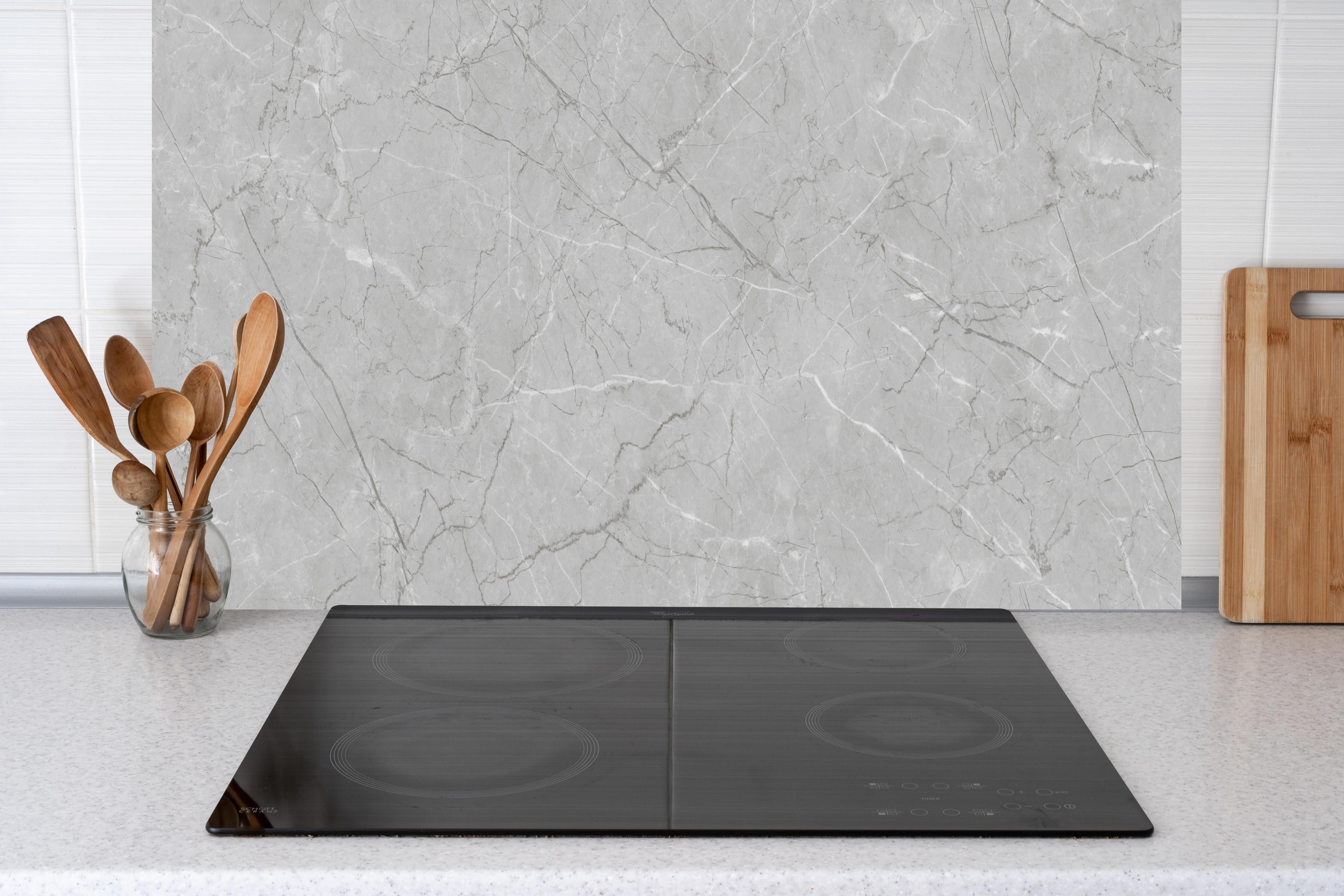 Küche - Minimalistische Marmorfläche in Weiß und Grau hinter Cerankochfeld und Holz-Kochutensilien