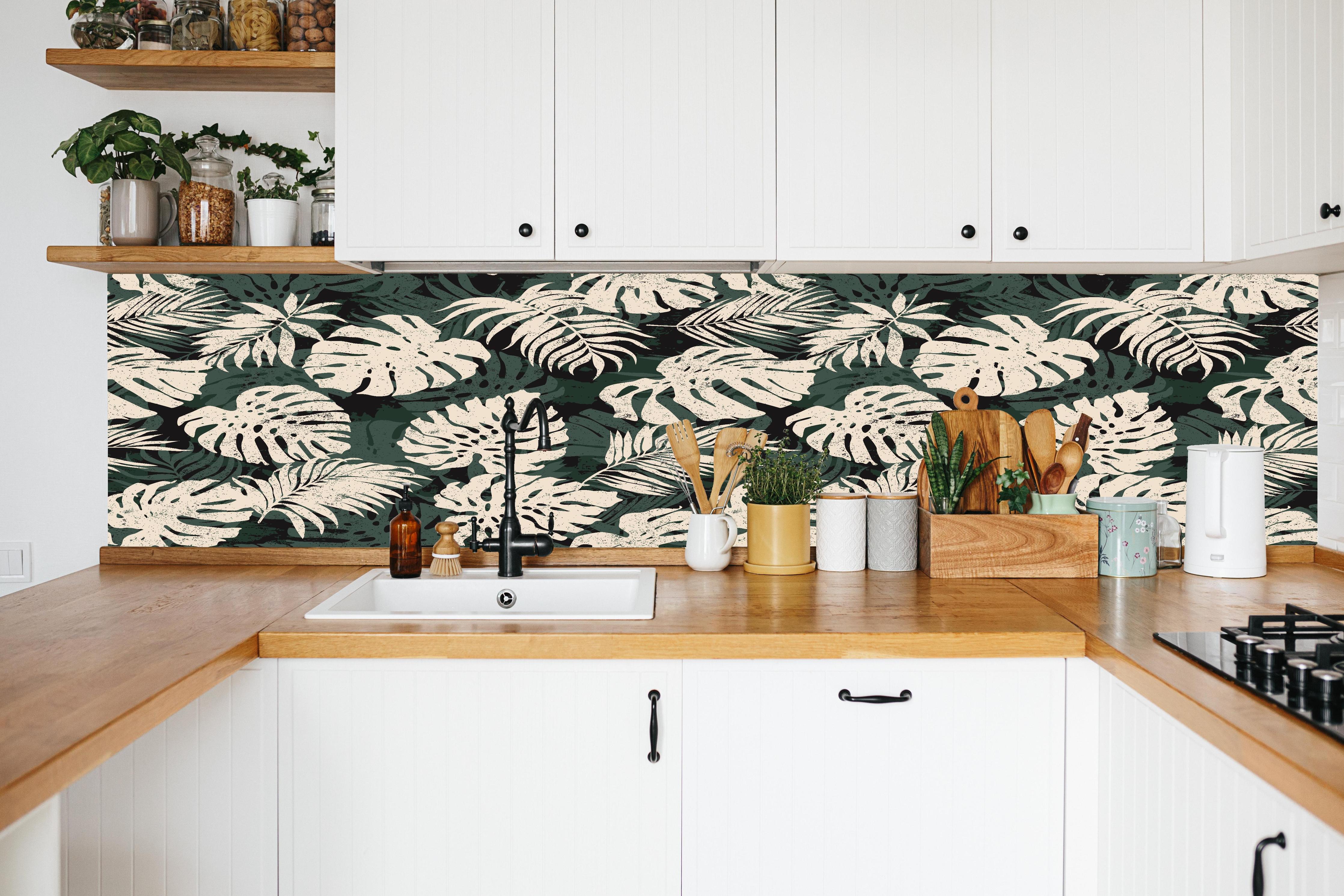 Küche - Monstera Blattmuster Grün-Beige in weißer Küche hinter Gewürzen und Kochlöffeln aus Holz