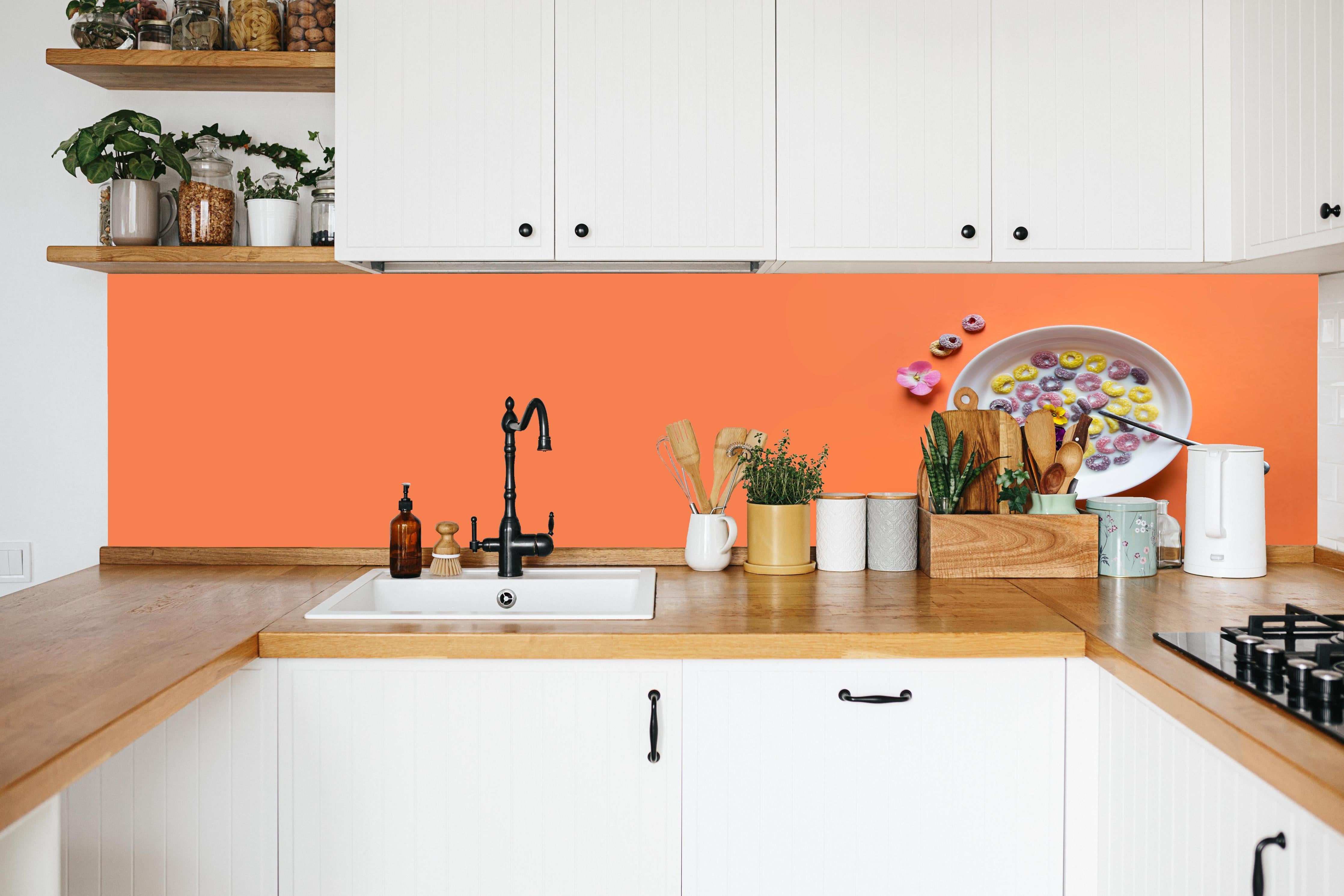 Küche - Orange Frühstücks-Bowl in weißer Küche hinter Gewürzen und Kochlöffeln aus Holz