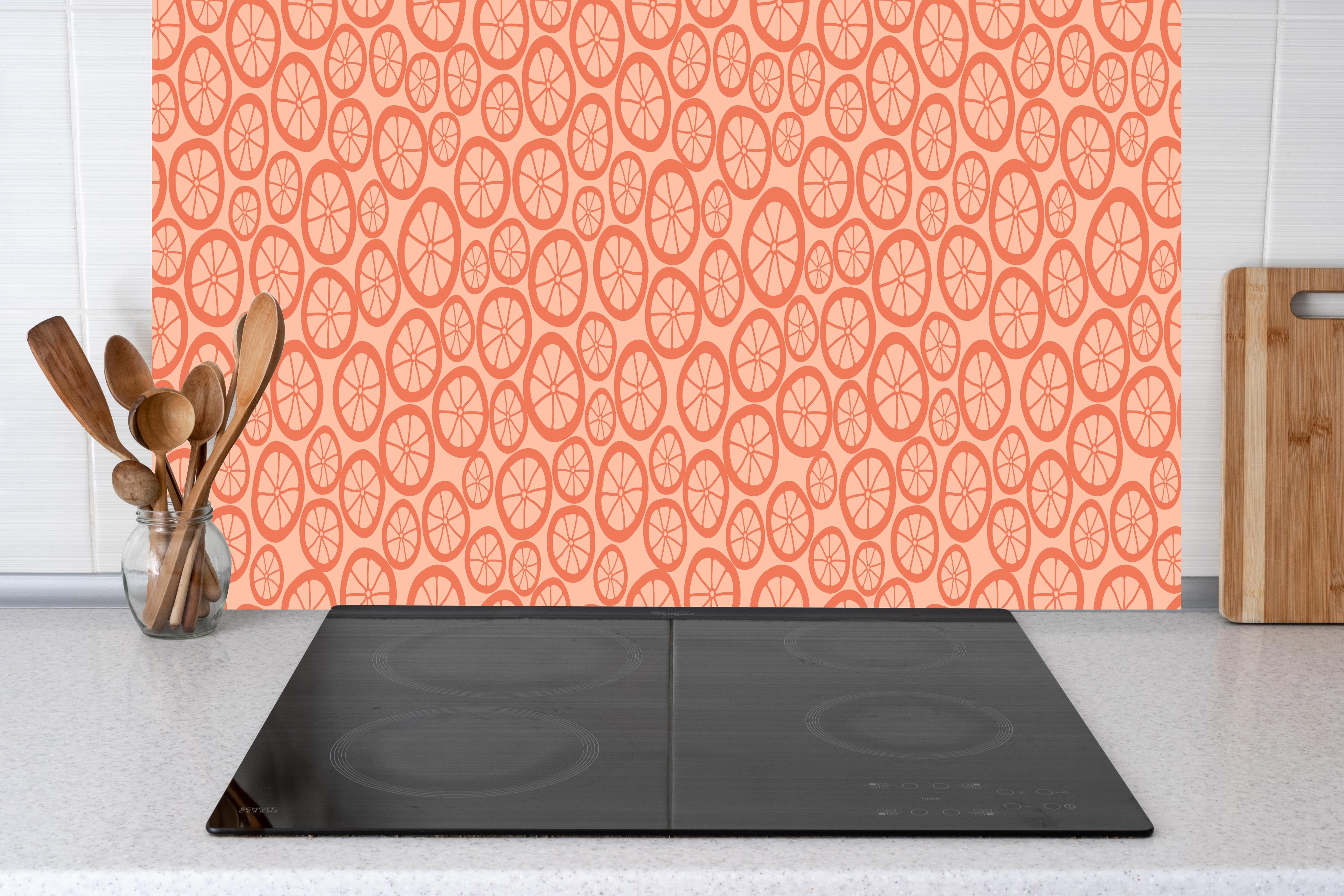 Küche - Orange Zitrus-Muster hinter Cerankochfeld und Holz-Kochutensilien