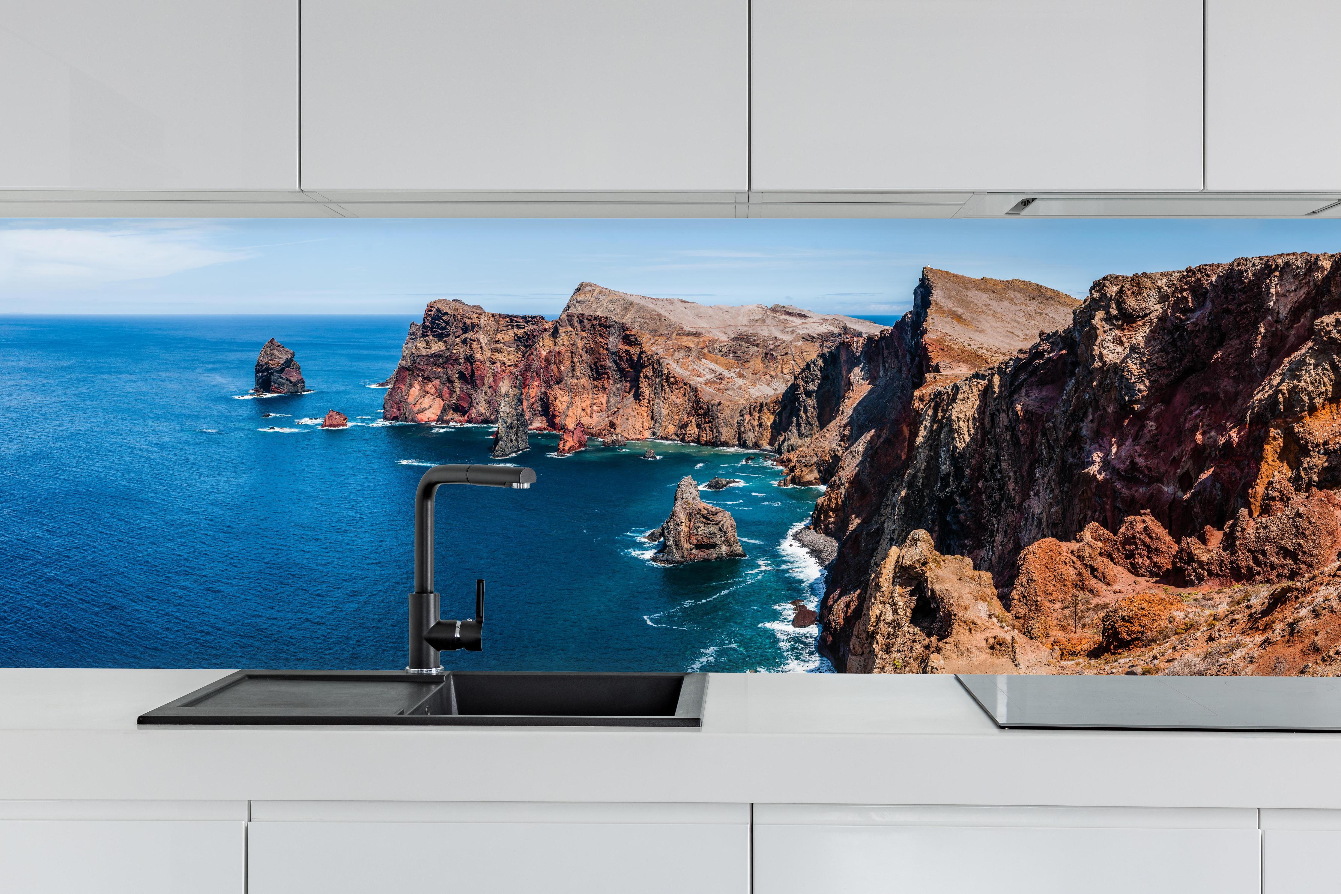 Küche - Portugal Felsklippen, Tiefes Blau hinter weißen Hochglanz-Küchenregalen und schwarzem Wasserhahn