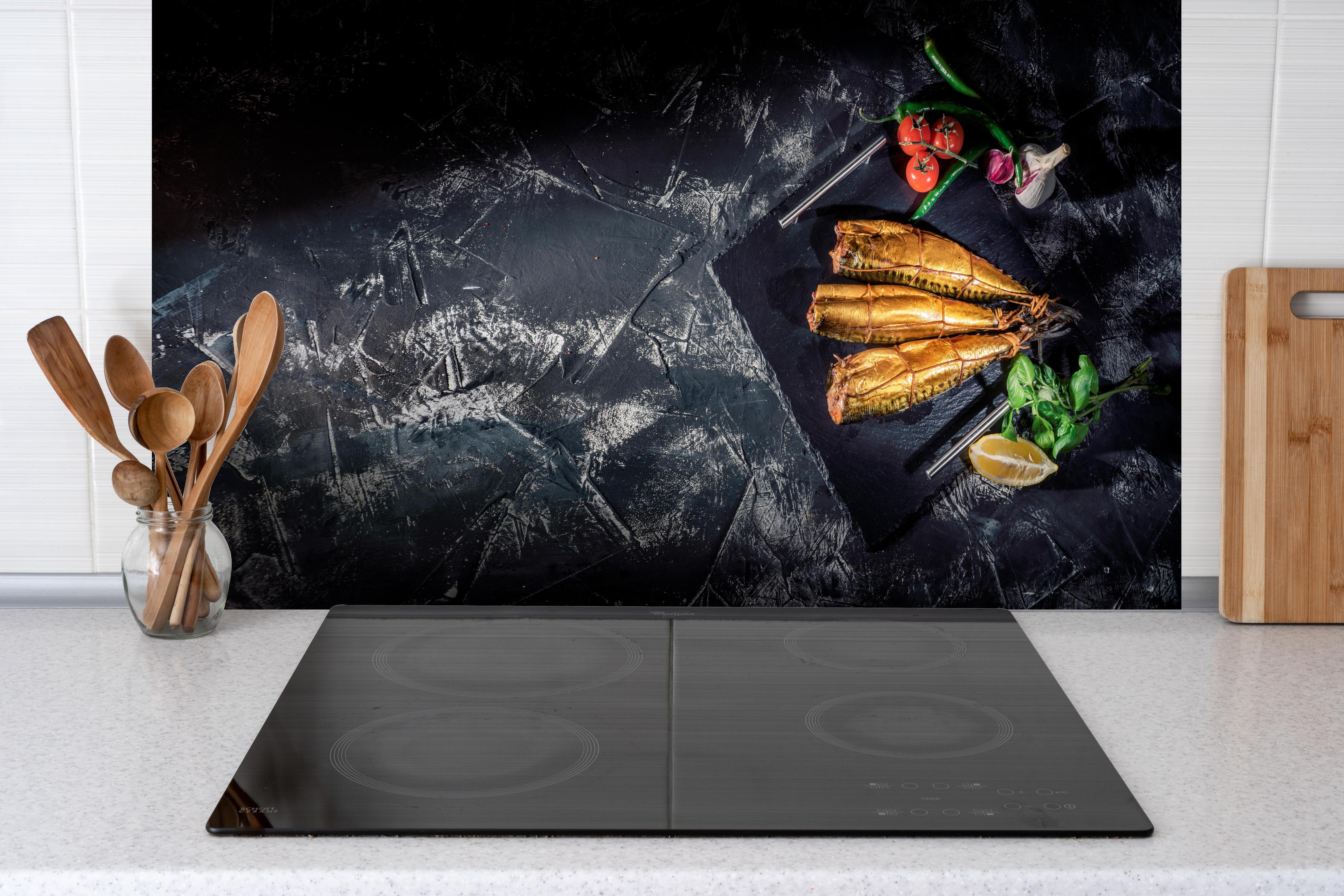 Küche - Räucherfisch auf dunklem Schiefer hinter Cerankochfeld und Holz-Kochutensilien